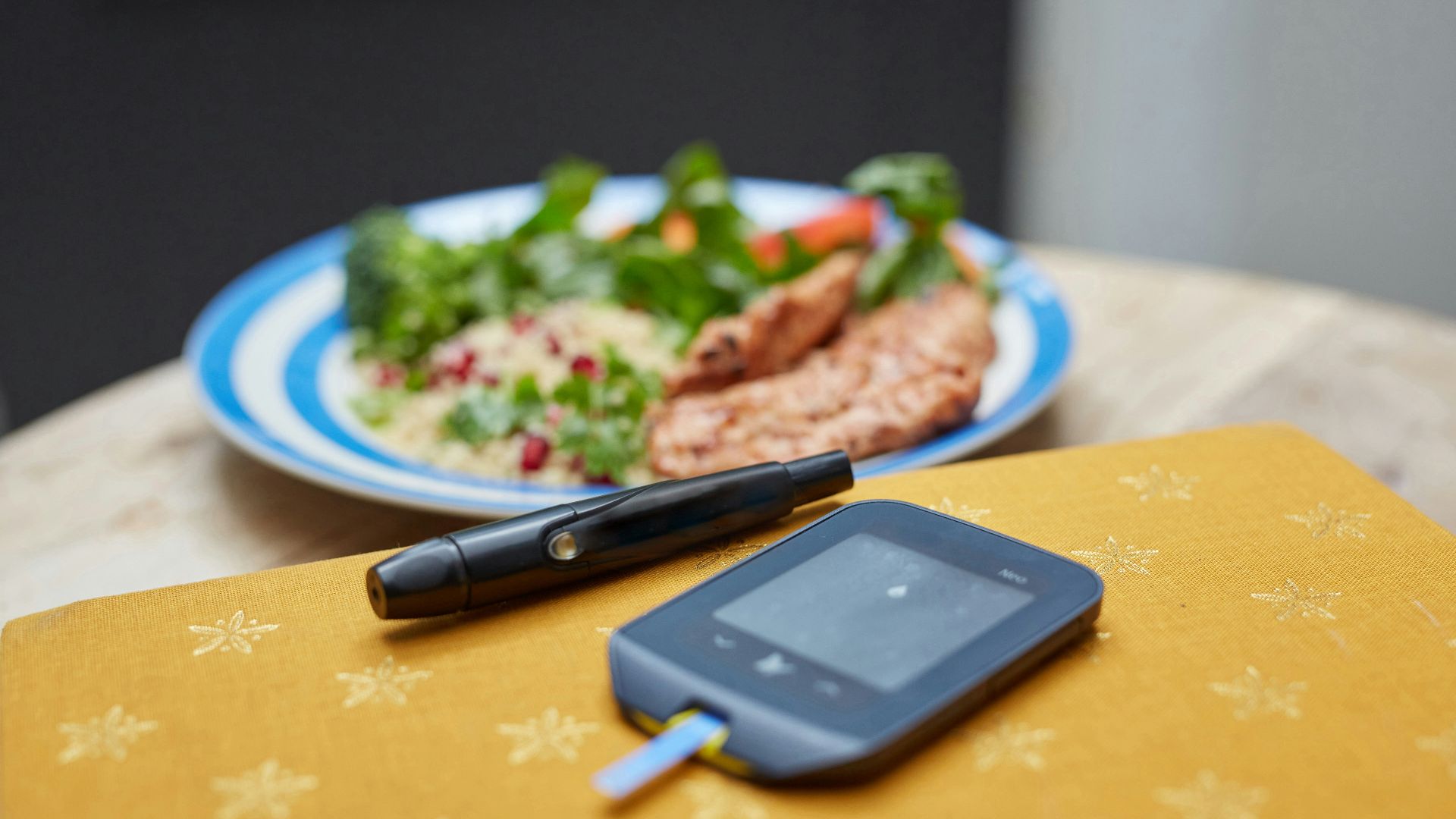a plate of food and a Glucometer on a table