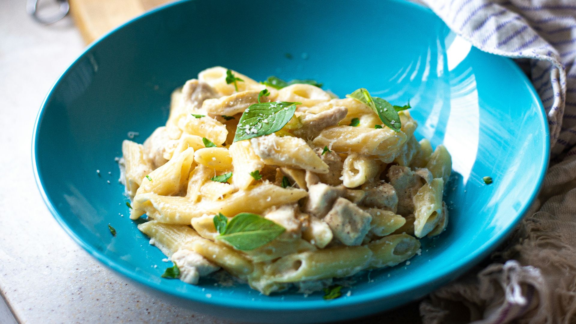 a blue bowl filled with pasta on top of a counter