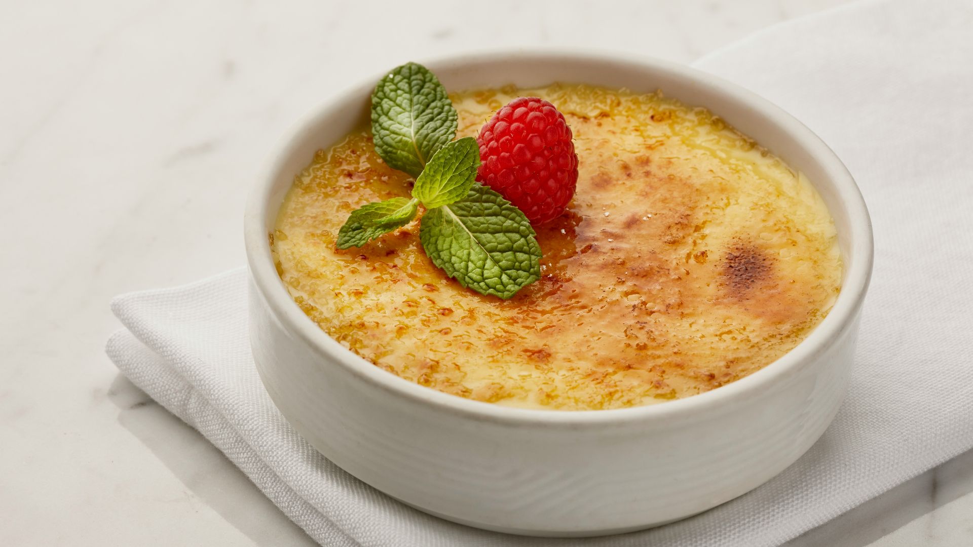 a bowl of pudding with a raspberry on top