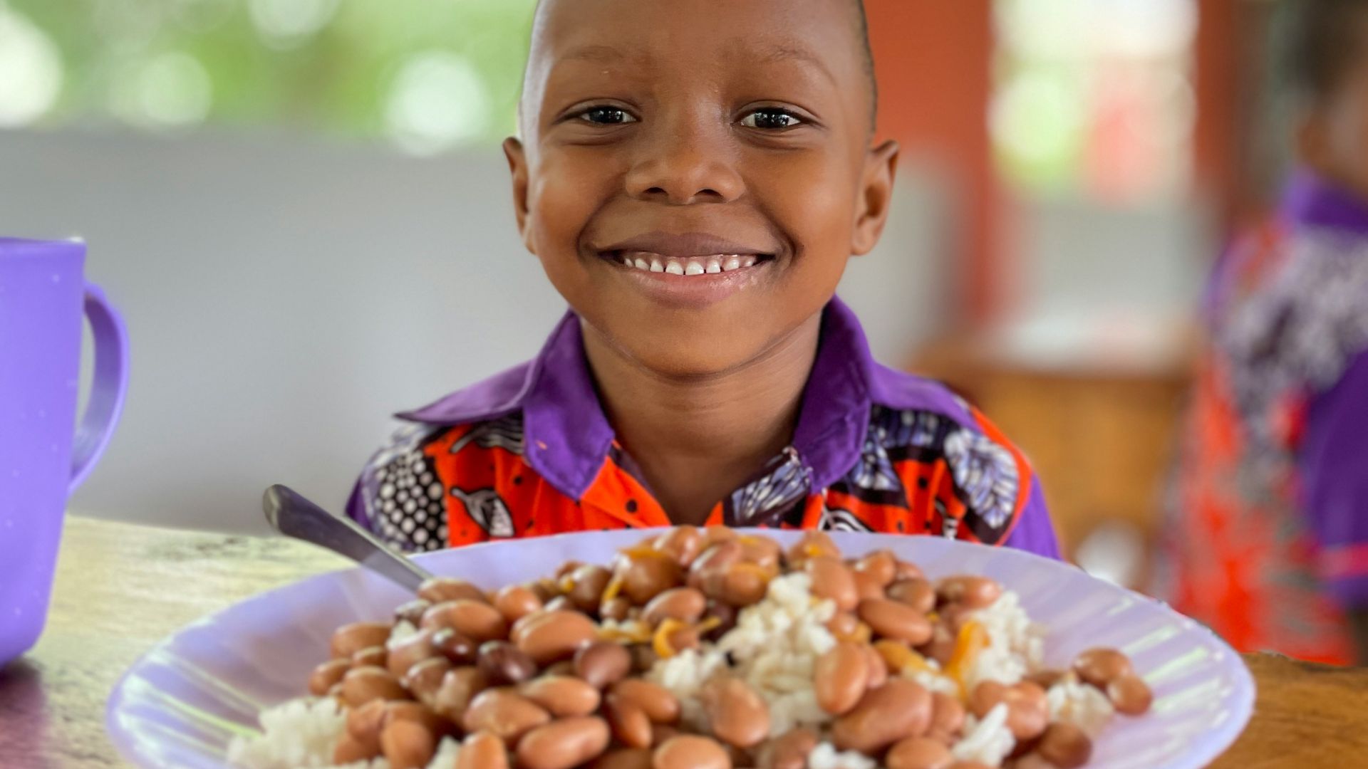 a young boy sitting at a table with a plate of food