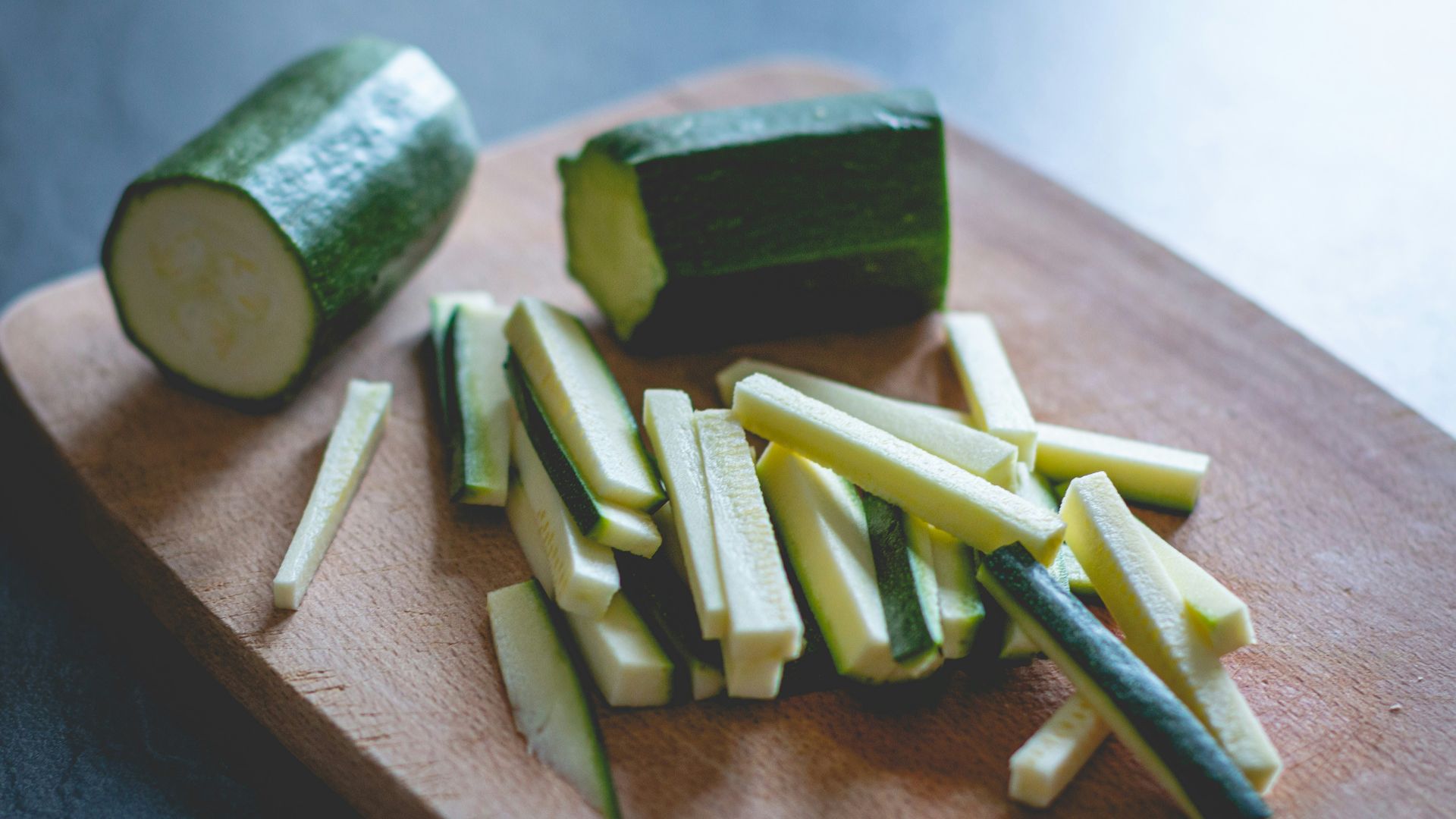 sliced green vegetable on brown wooden chopping board