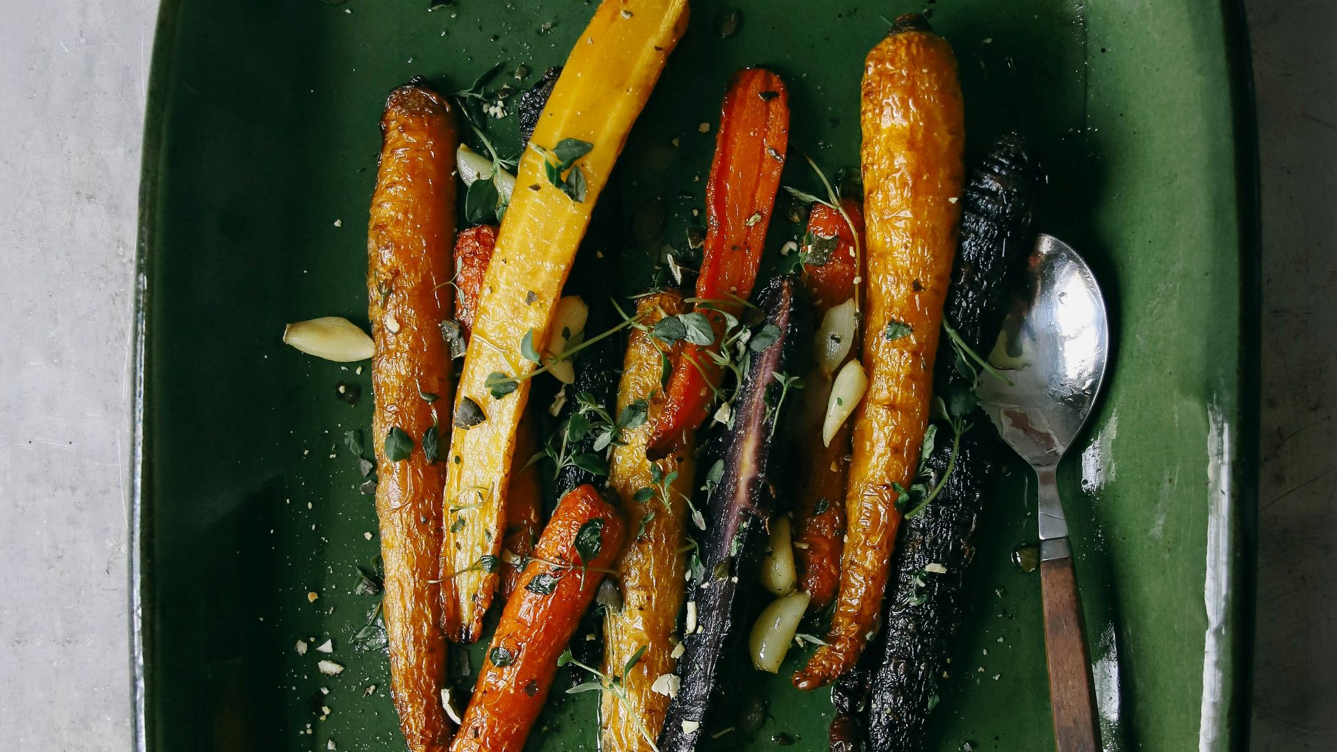 a green plate topped with carrots and other vegetables