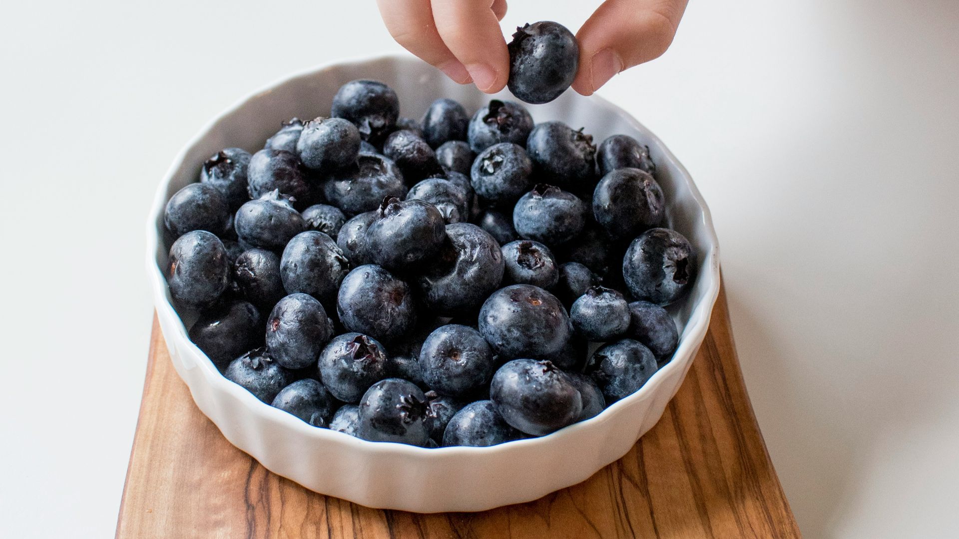 person holding bowl of black berries