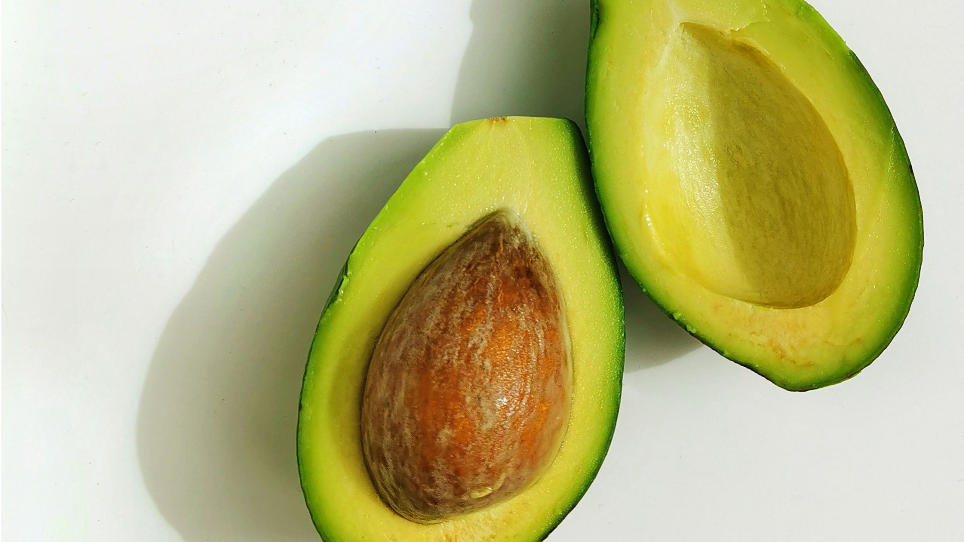 an avocado cut in half on a white surface