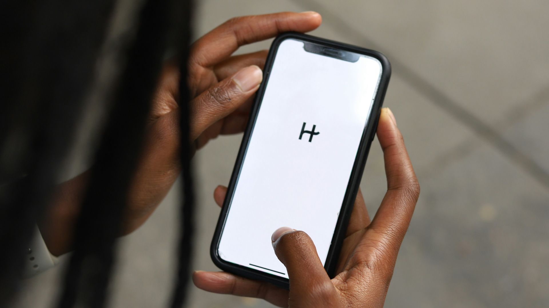 a woman holding a cell phone with a h on the screen