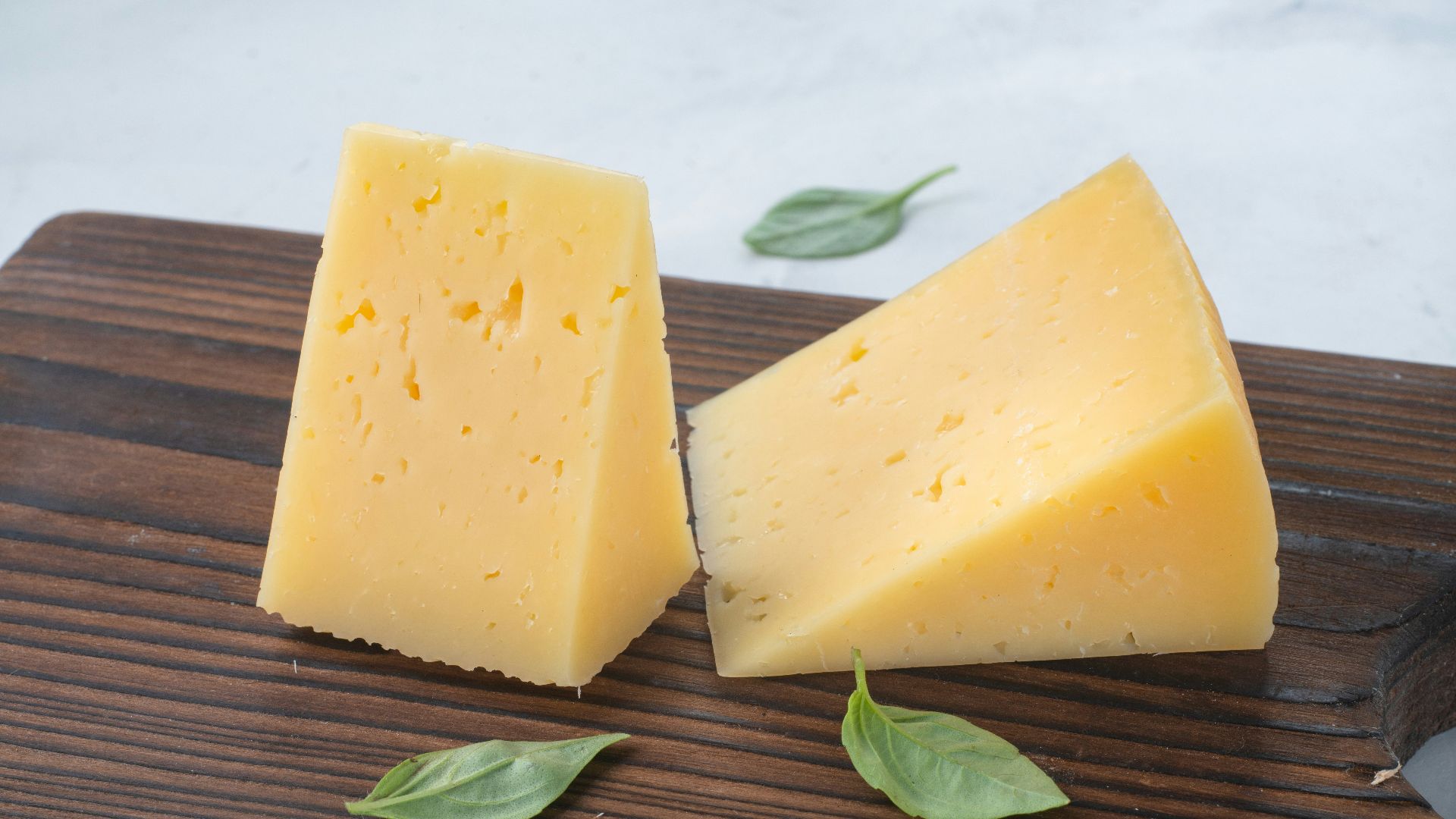 a couple of pieces of cheese sitting on top of a wooden cutting board
