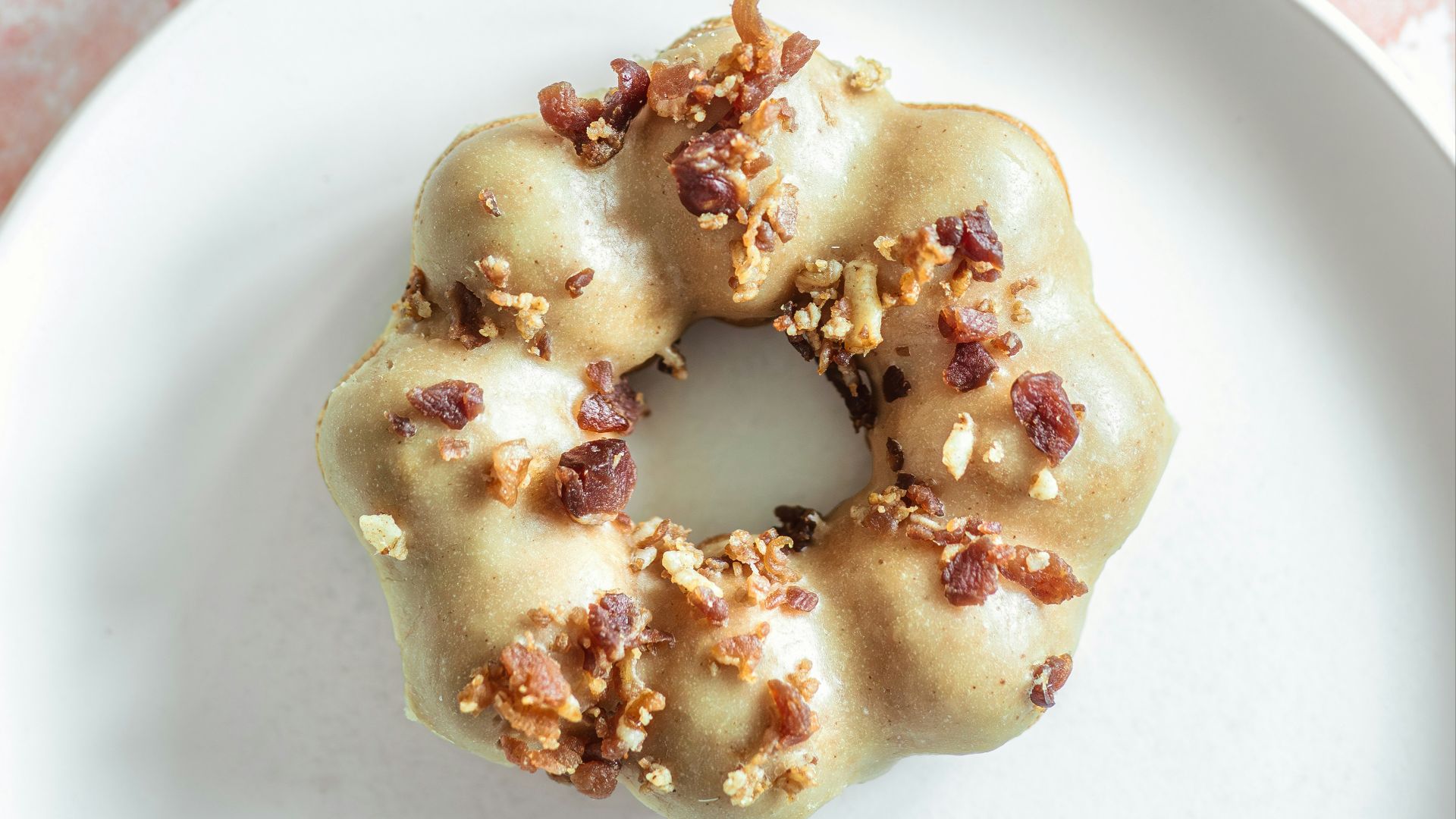 a white plate topped with a donut covered in nuts