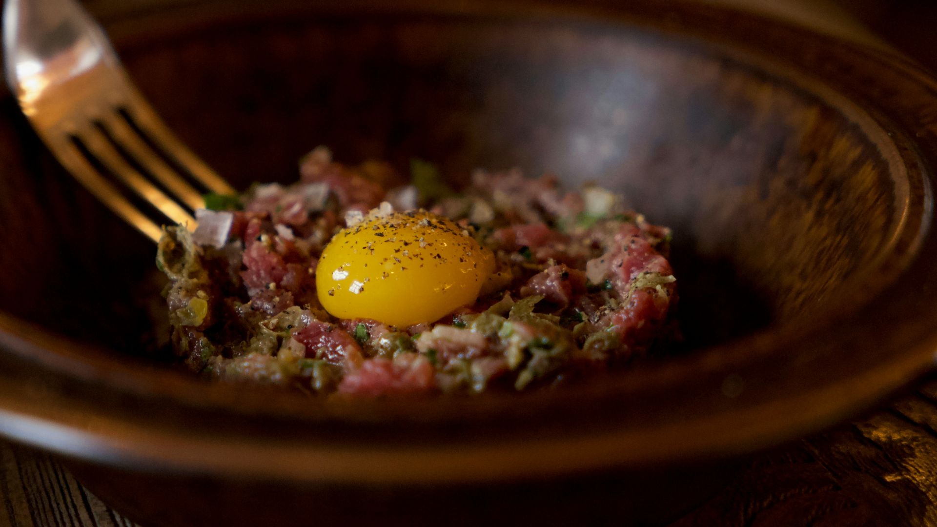egg-topped meat dish in round brown bowl