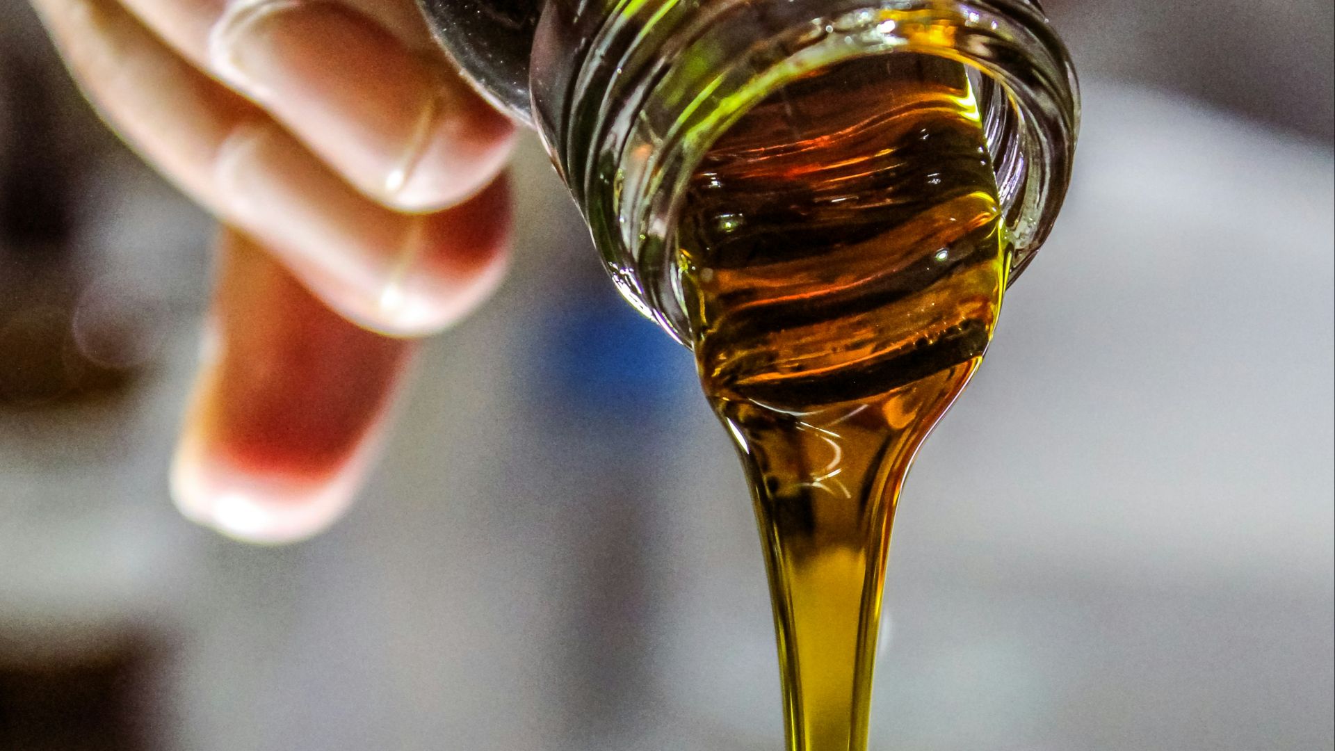 person holding clear drinking glass with brown liquid