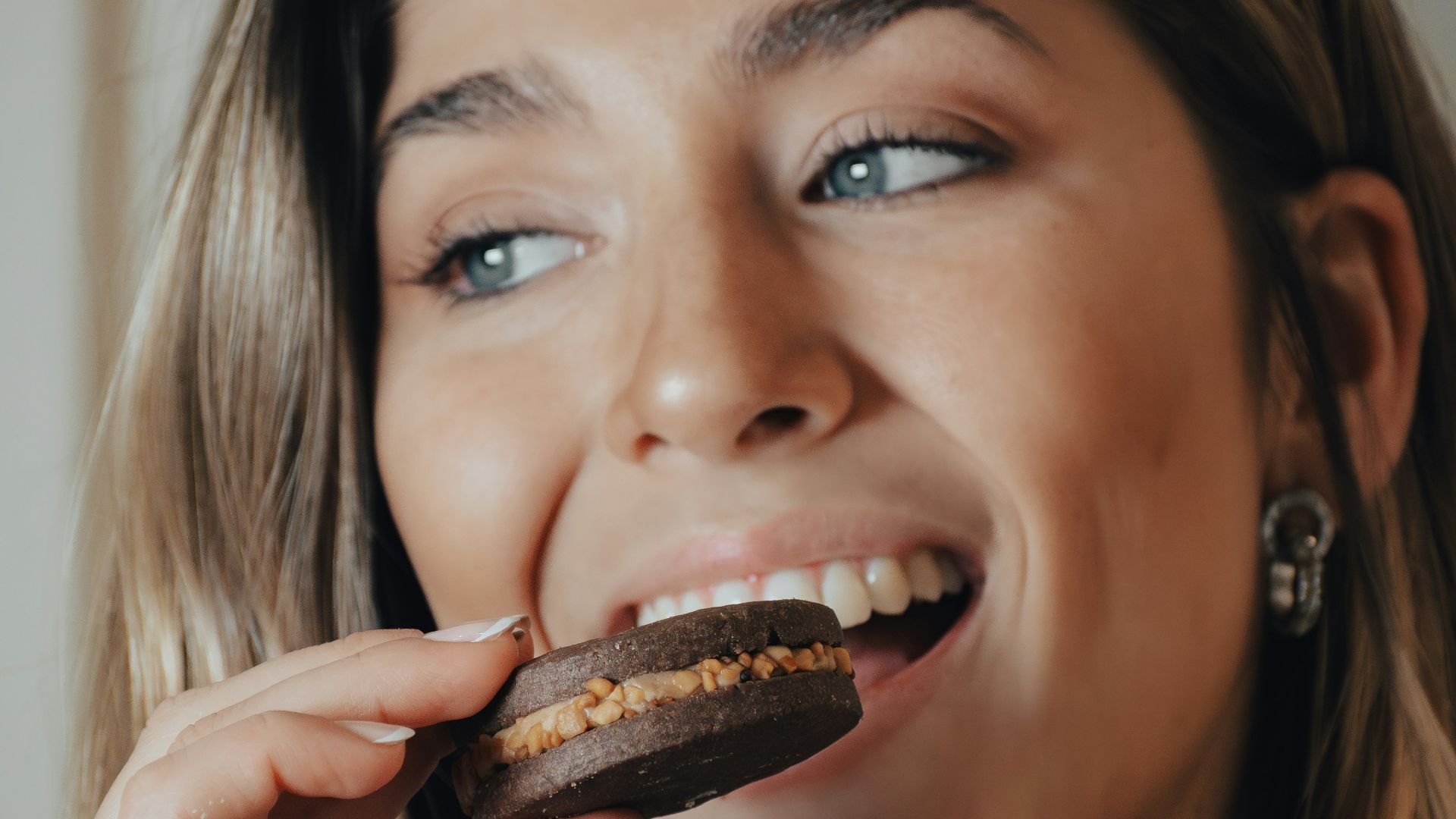 a woman is eating a chocolate doughnut and drinking a cup of coffee