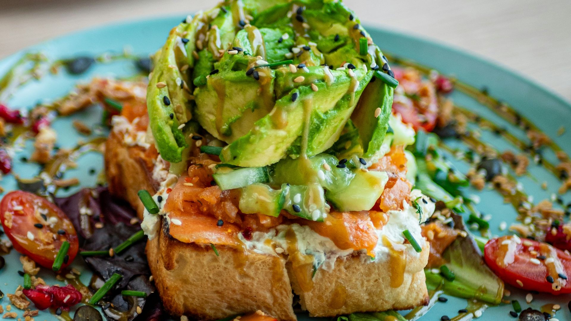 a blue plate topped with a piece of bread covered in veggies