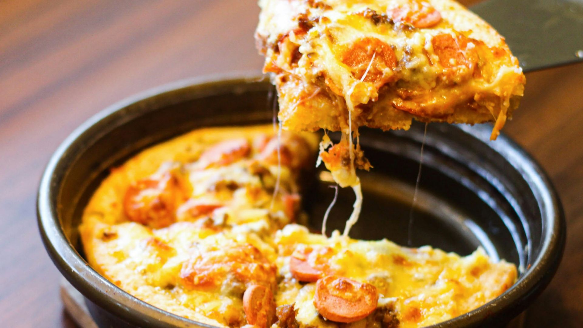a person taking a slice of pizza from a pan