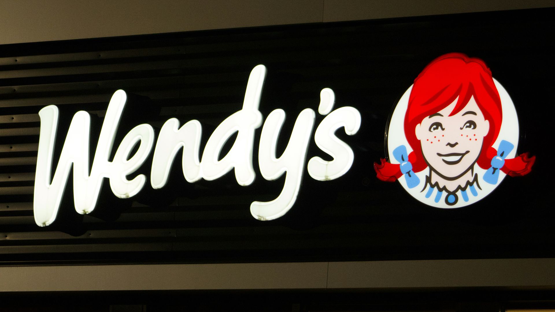 A wendy's sign is lit up at night