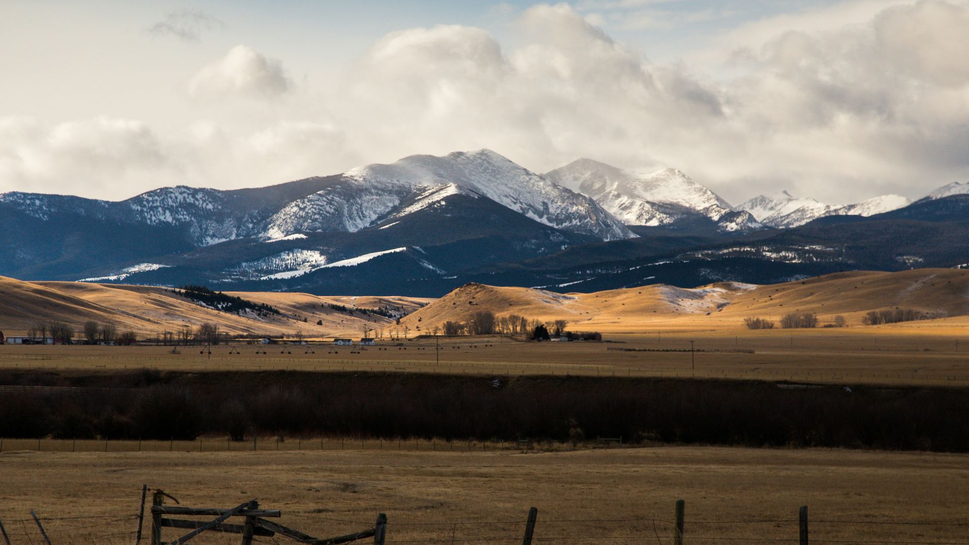 brown field near mountains under white clouds during daytime