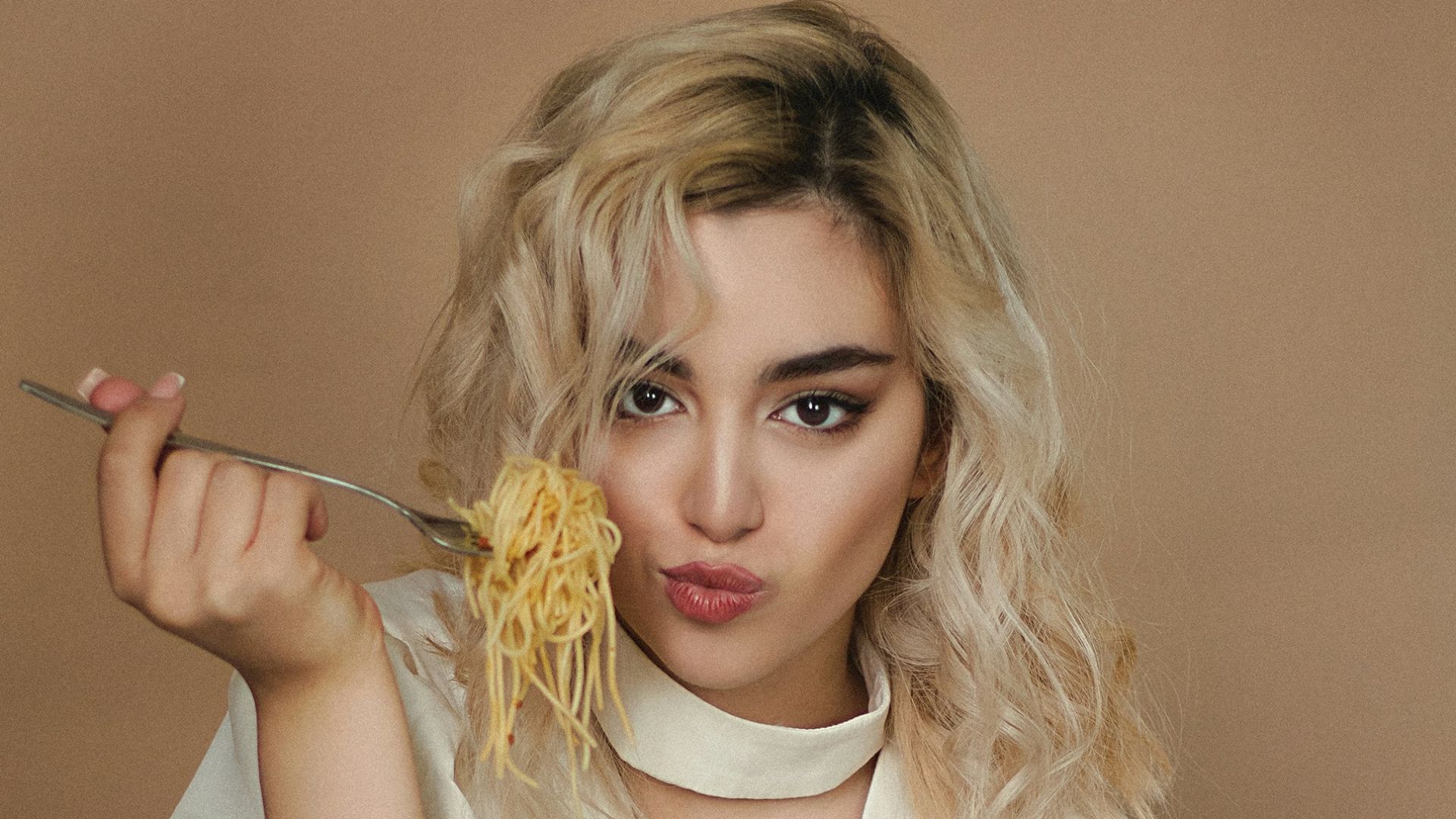 woman in white dress shirt eating pizza