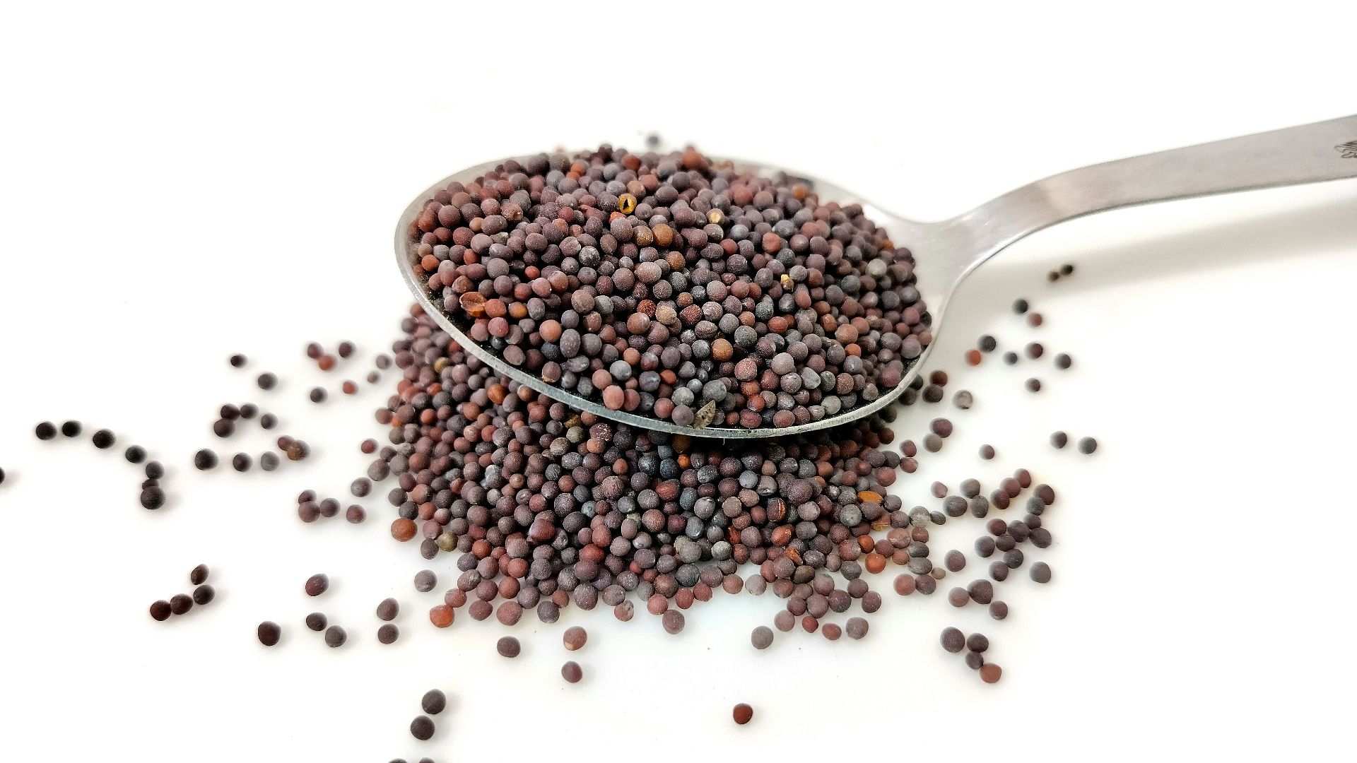 a spoon filled with black seed on top of a white table