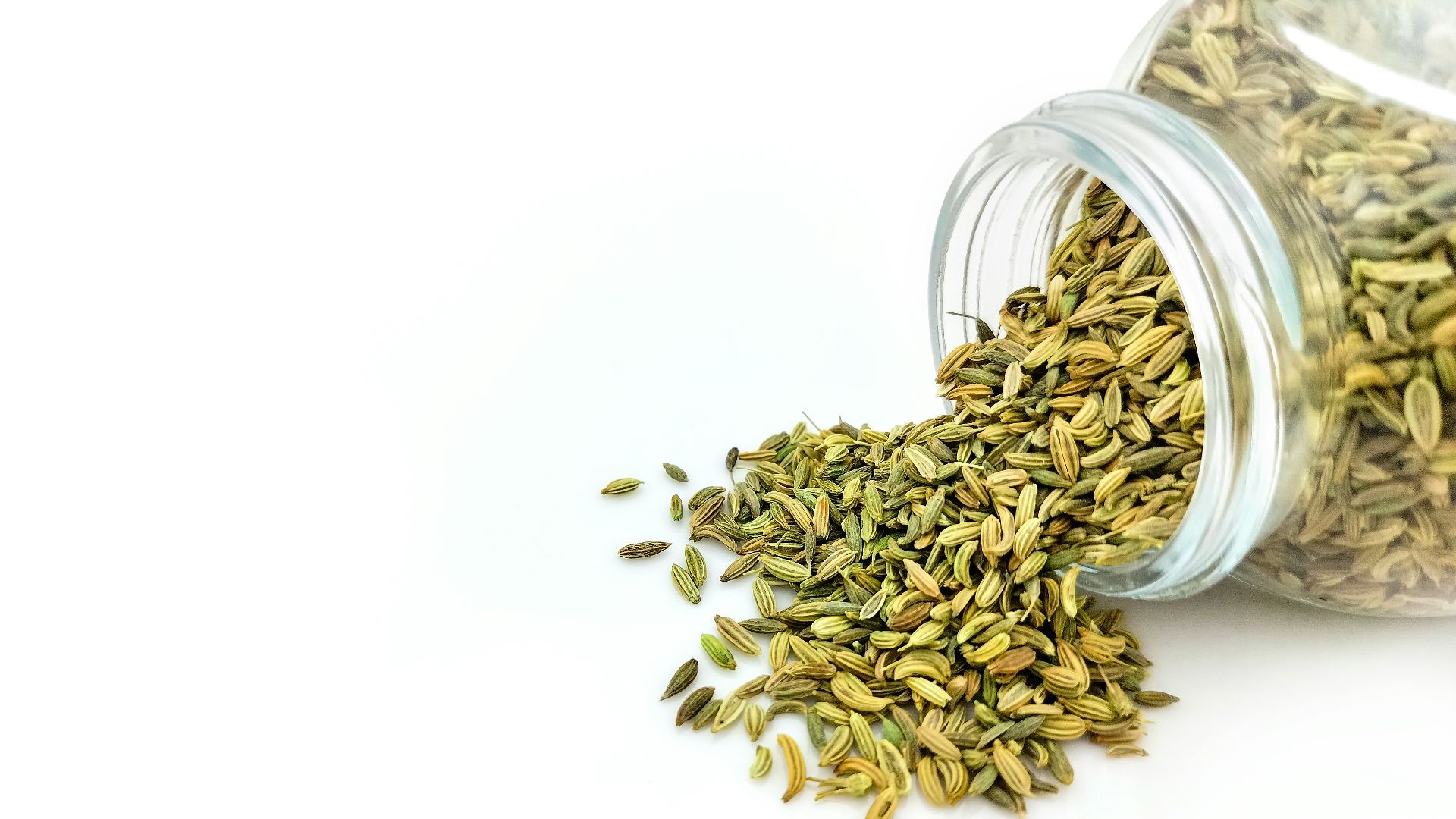 a glass jar filled with seeds on top of a white table