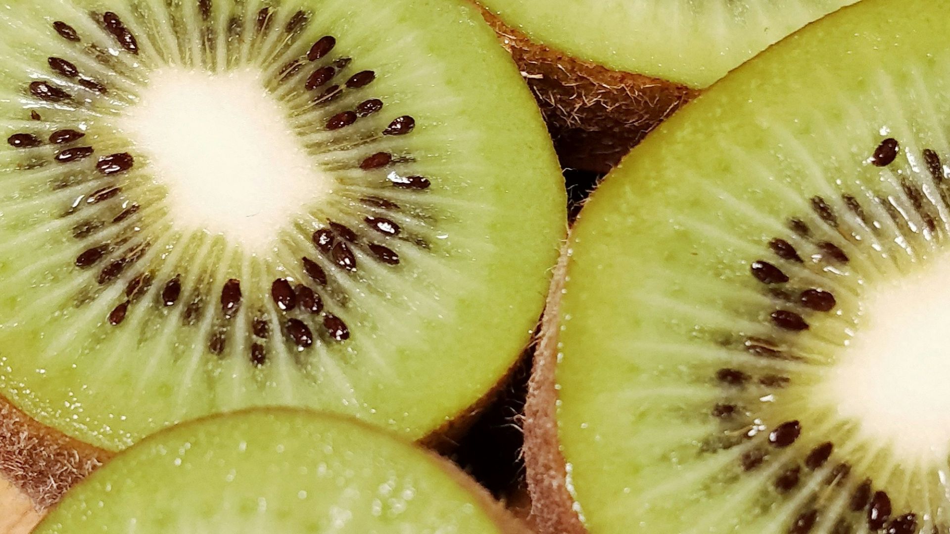 a bunch of kiwi cut in half on a cutting board