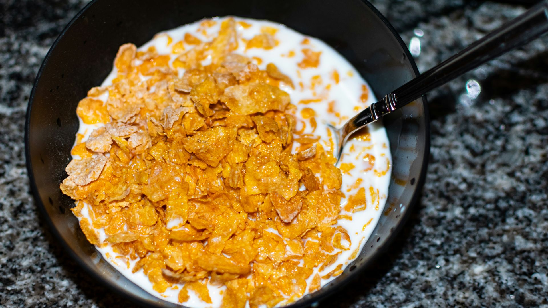 Cornflakes and milk sit in a bowl.