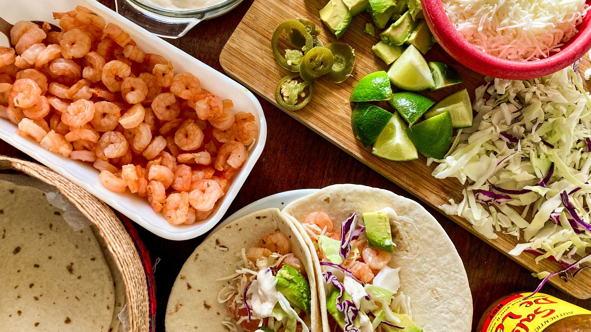 a table topped with tacos, guacamole and other foods