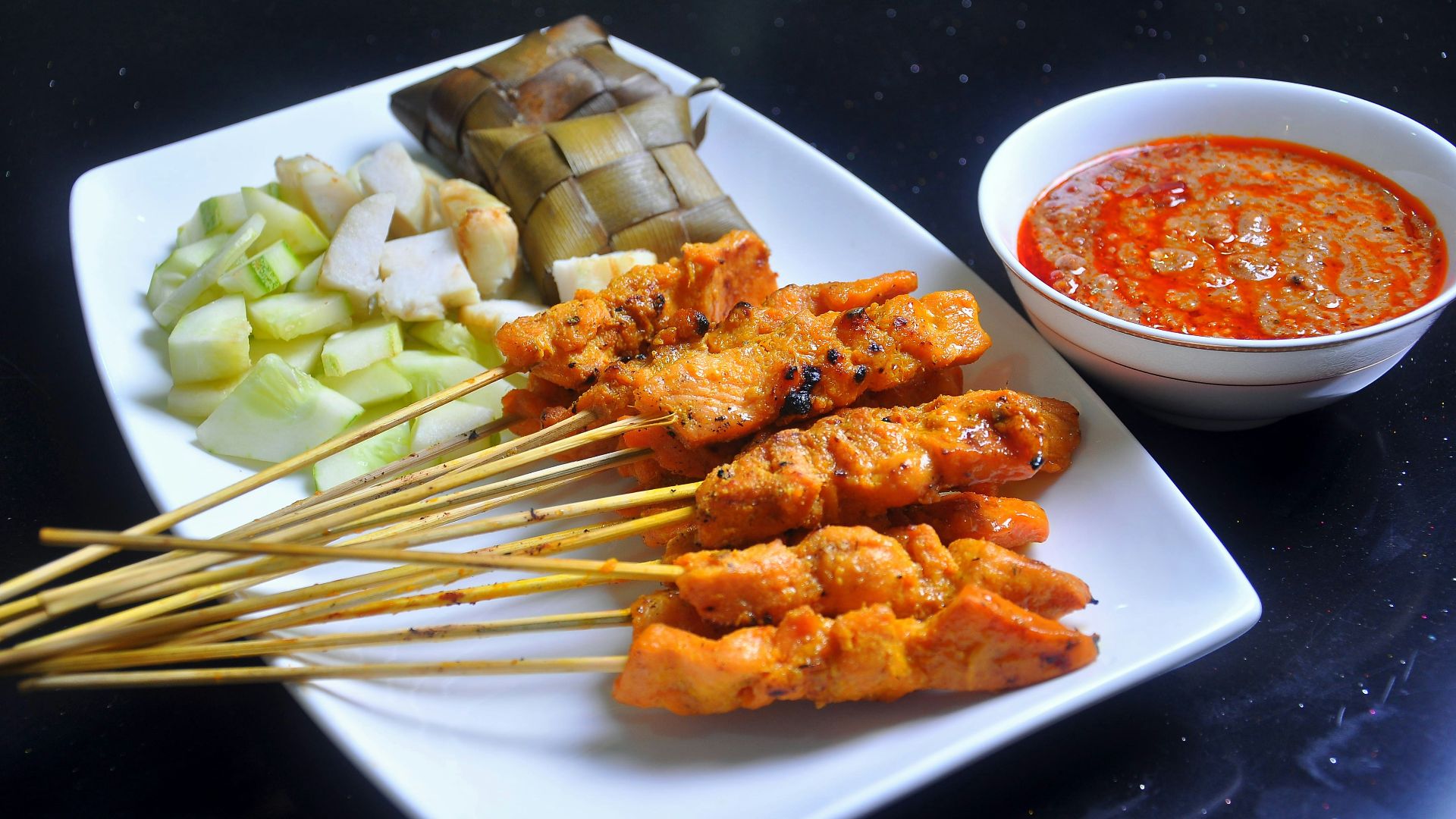 a white plate topped with meat and veggies next to a bowl of sauce