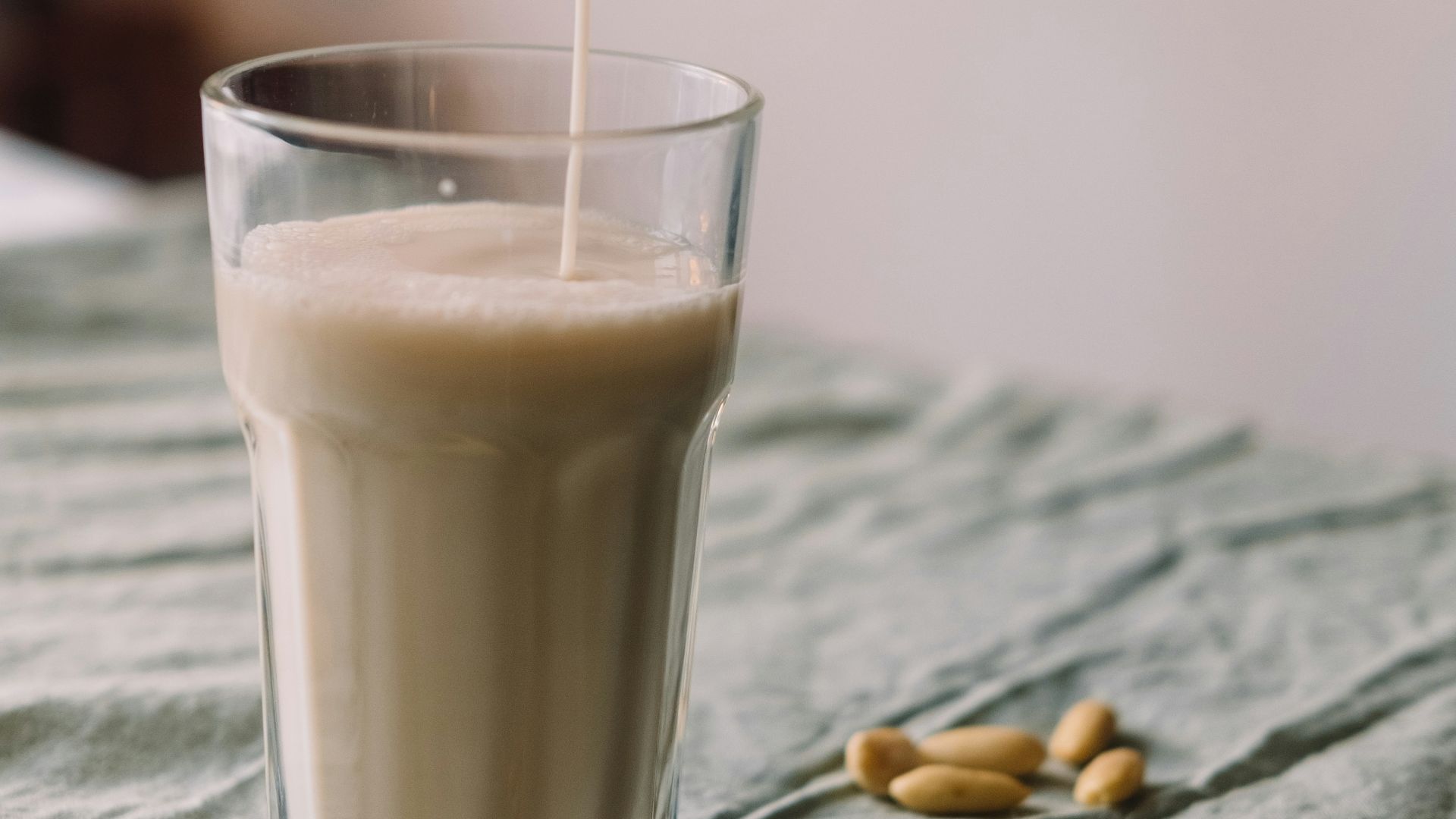a person pouring milk into a glass on top of a bed