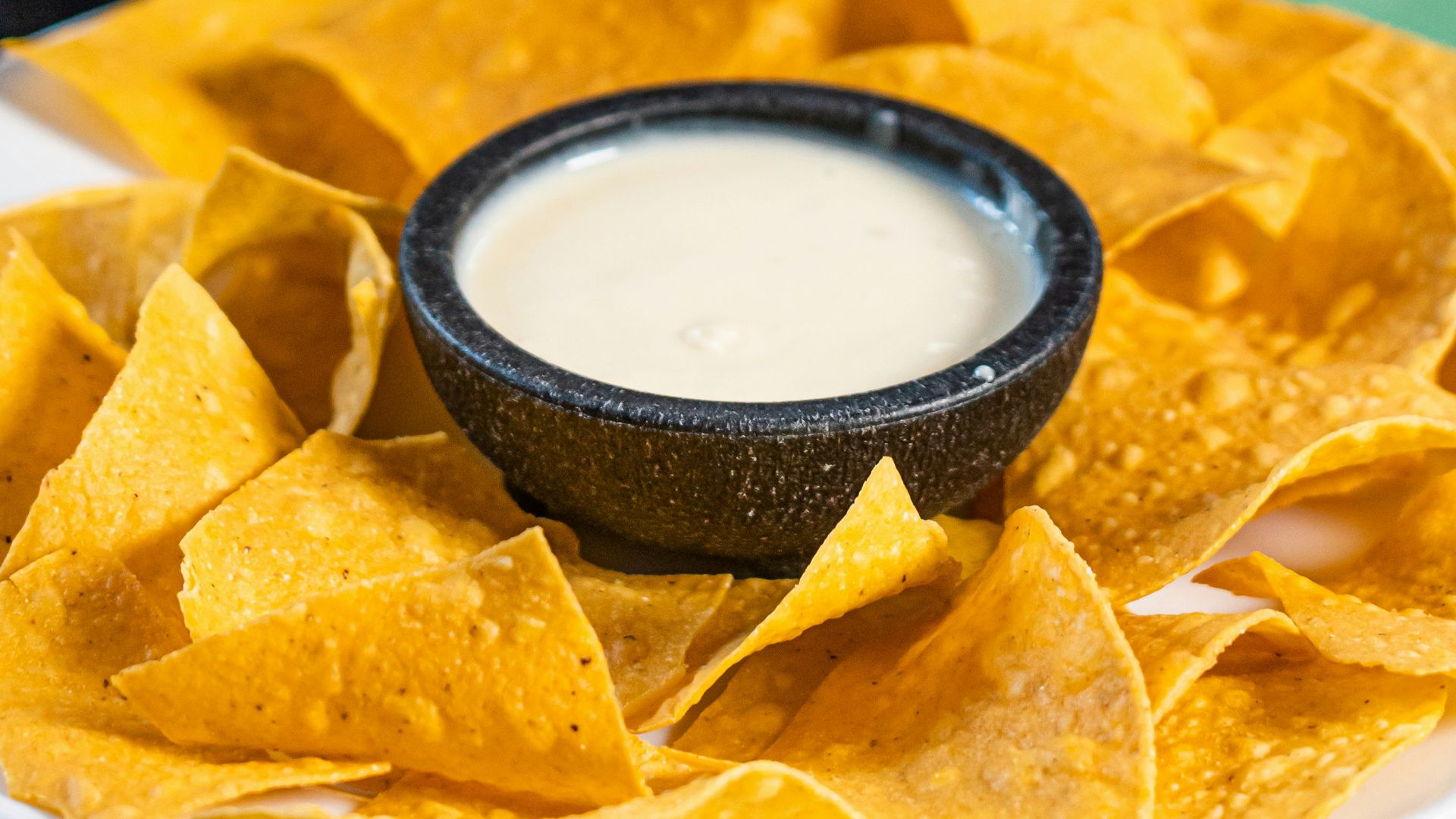 a person dipping a tortilla into a bowl of salsa