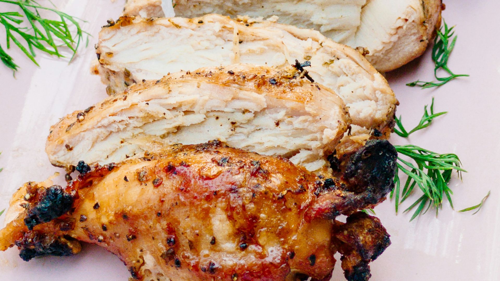 a pink plate topped with meat covered in sauce