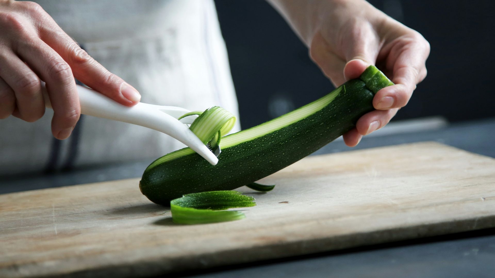 person pealing green cucumber inside room