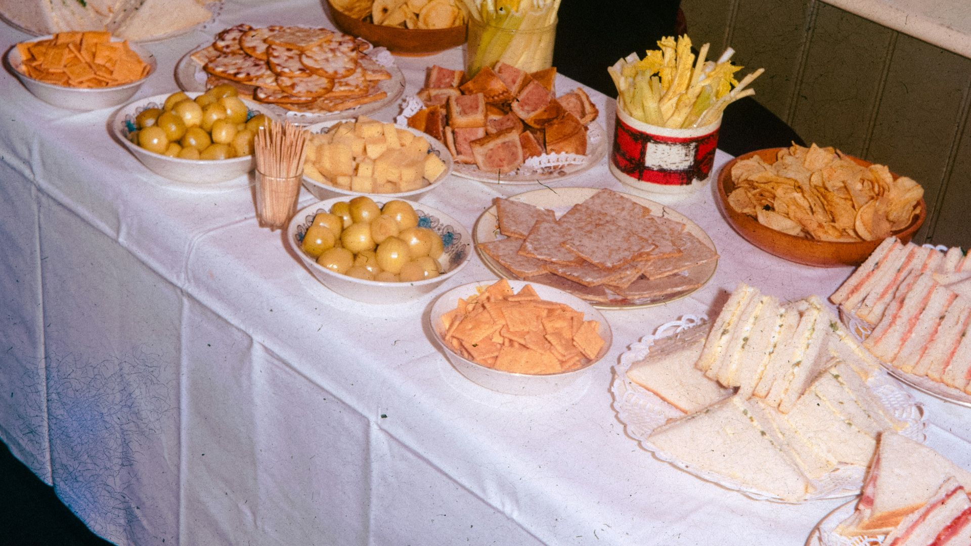 A table laden with various party snacks and sandwiches.