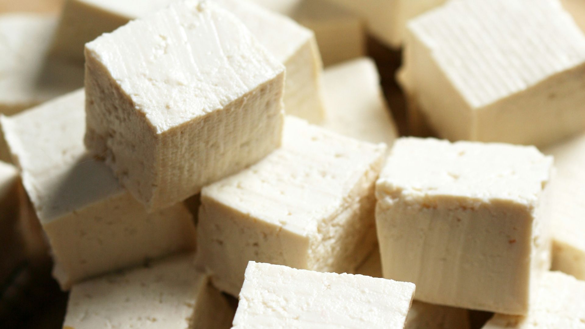 A pile of tofu cubes sitting on top of a cutting board