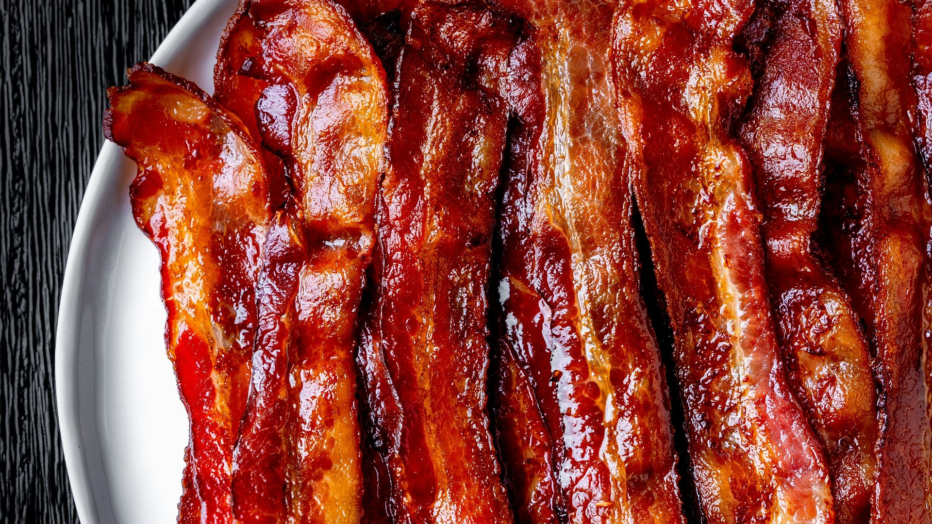 a white plate topped with bacon strips on top of a table