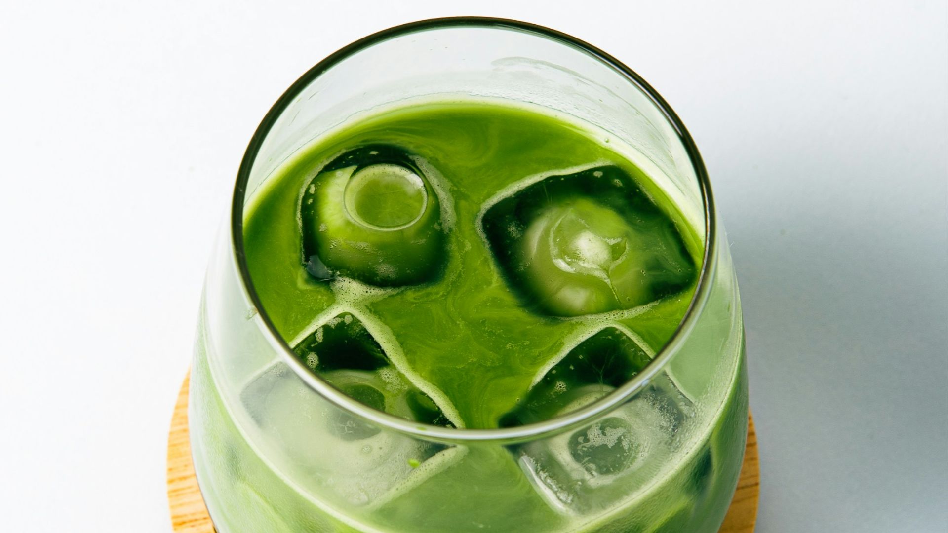 a green drink with ice cubes in it