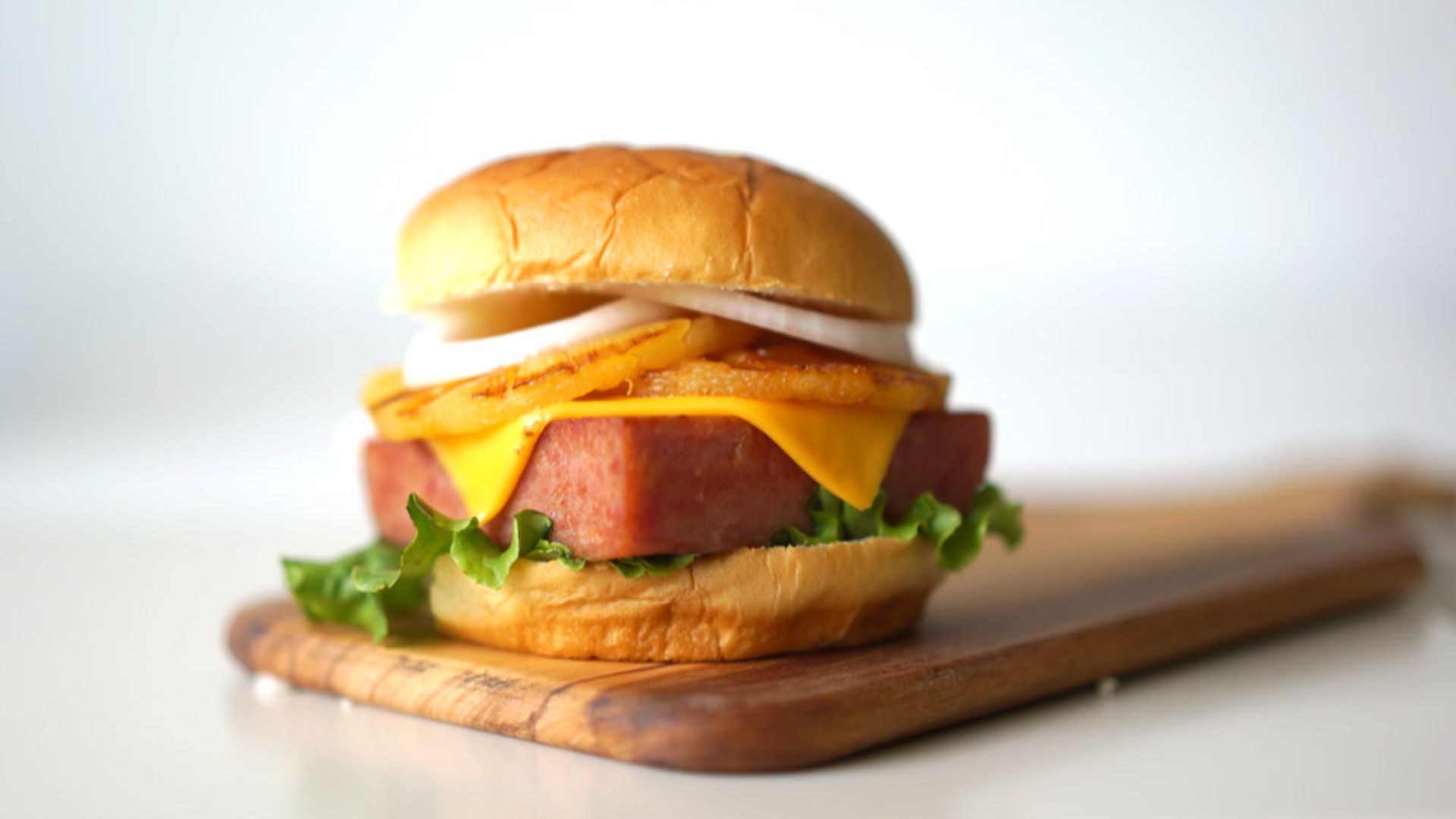 File:Burger hamburger Hawaiian spam luncheon meat patty grilled pineapple lettuce onion American cheese teriyaki sauce hawaiian sweet roll bun cutting board (27801929284).jpg