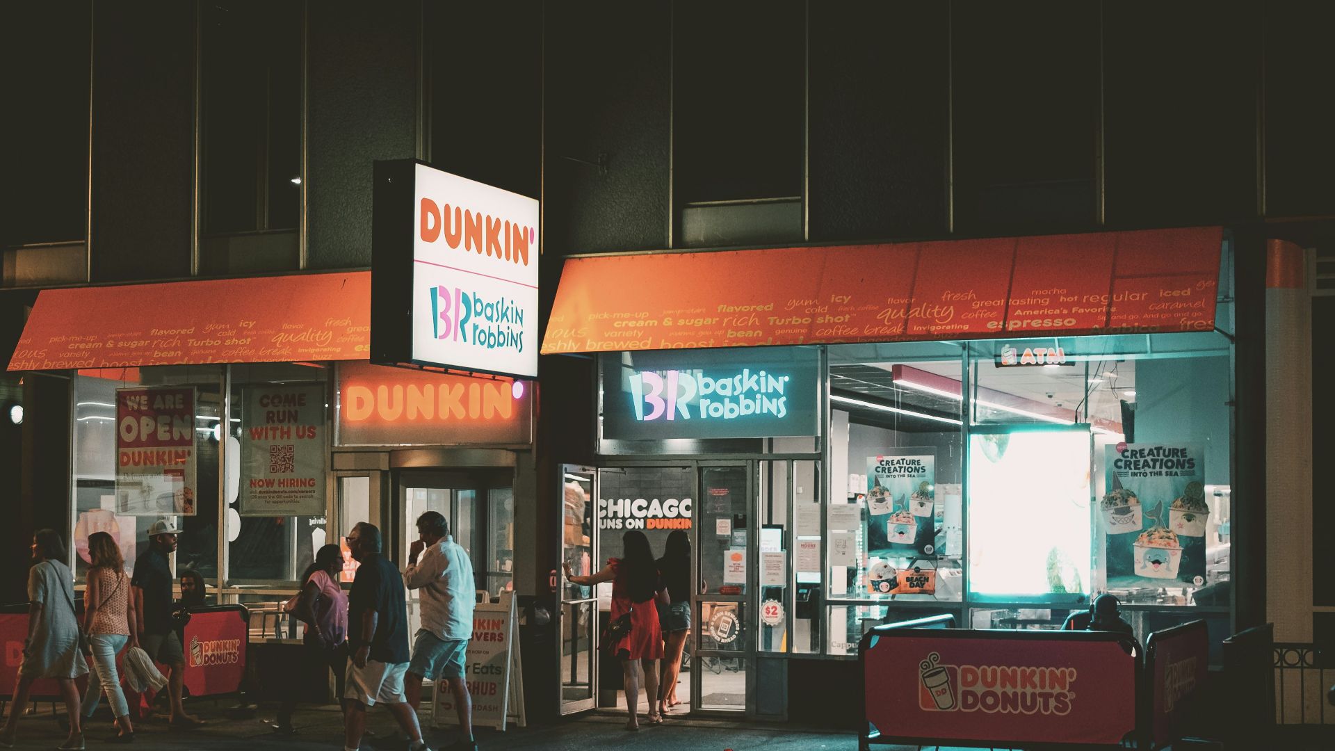 a group of people standing outside of a store at night