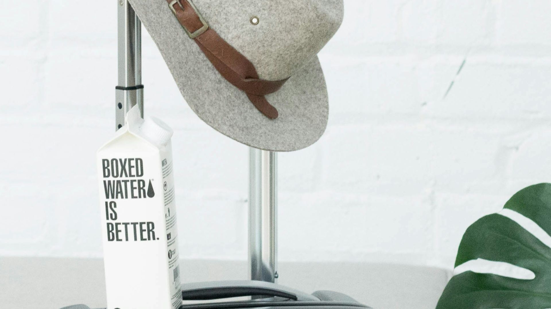 A hat and Boxed Water carton sit on a suitcase