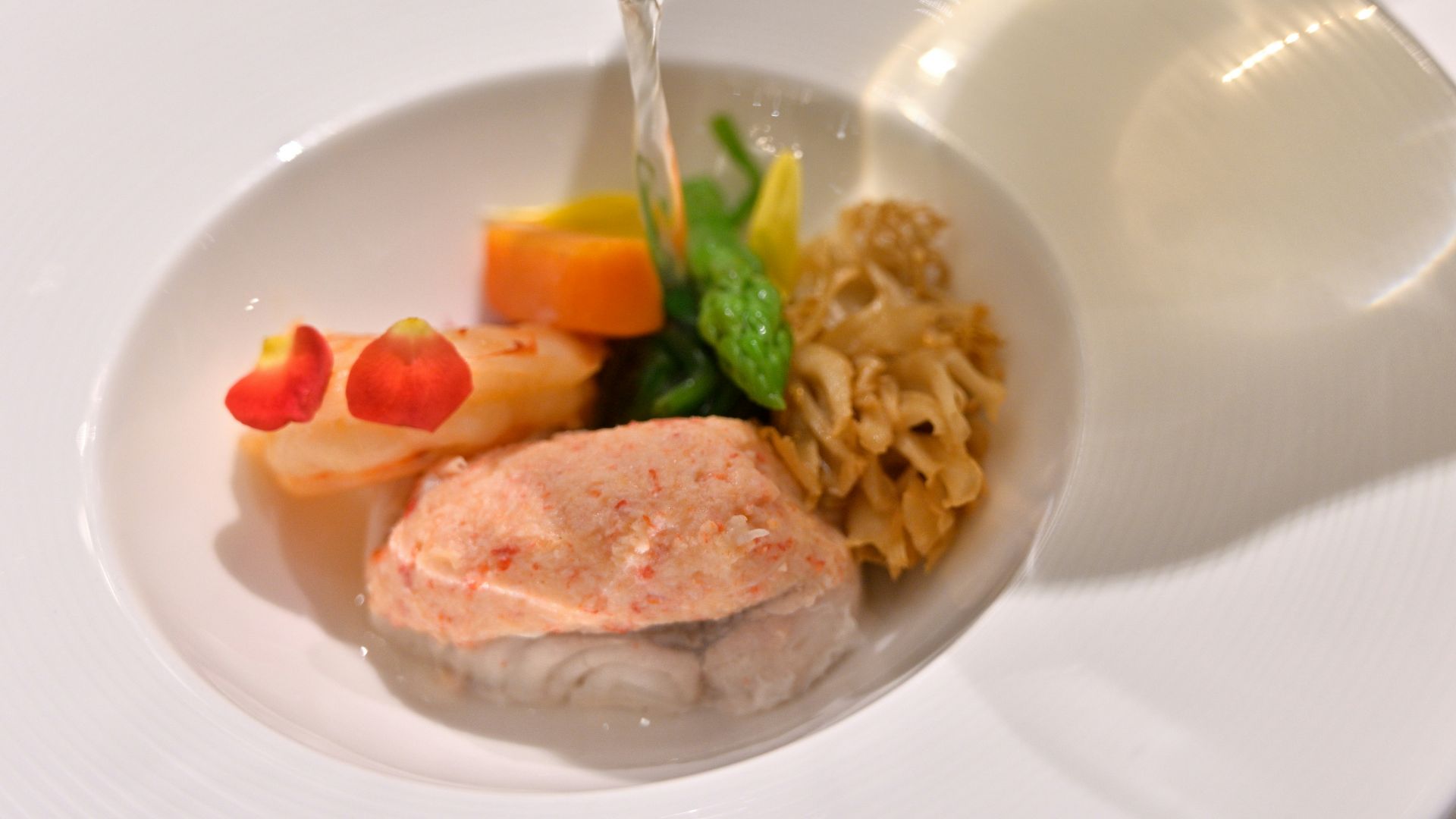 a white plate topped with meat and veggies next to a glass of wine
