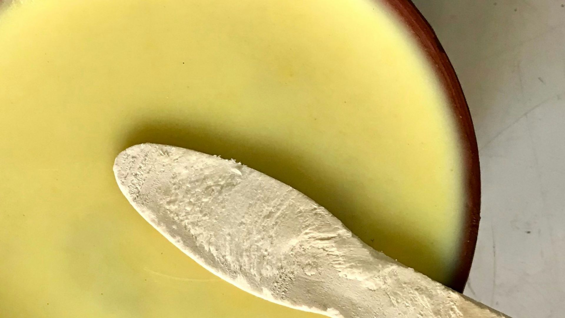 A spoon in a bowl with a liquid inside of it