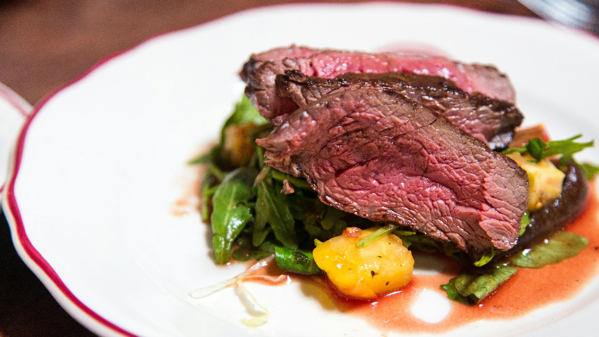 medium rare sliced steak in white ceramic plate