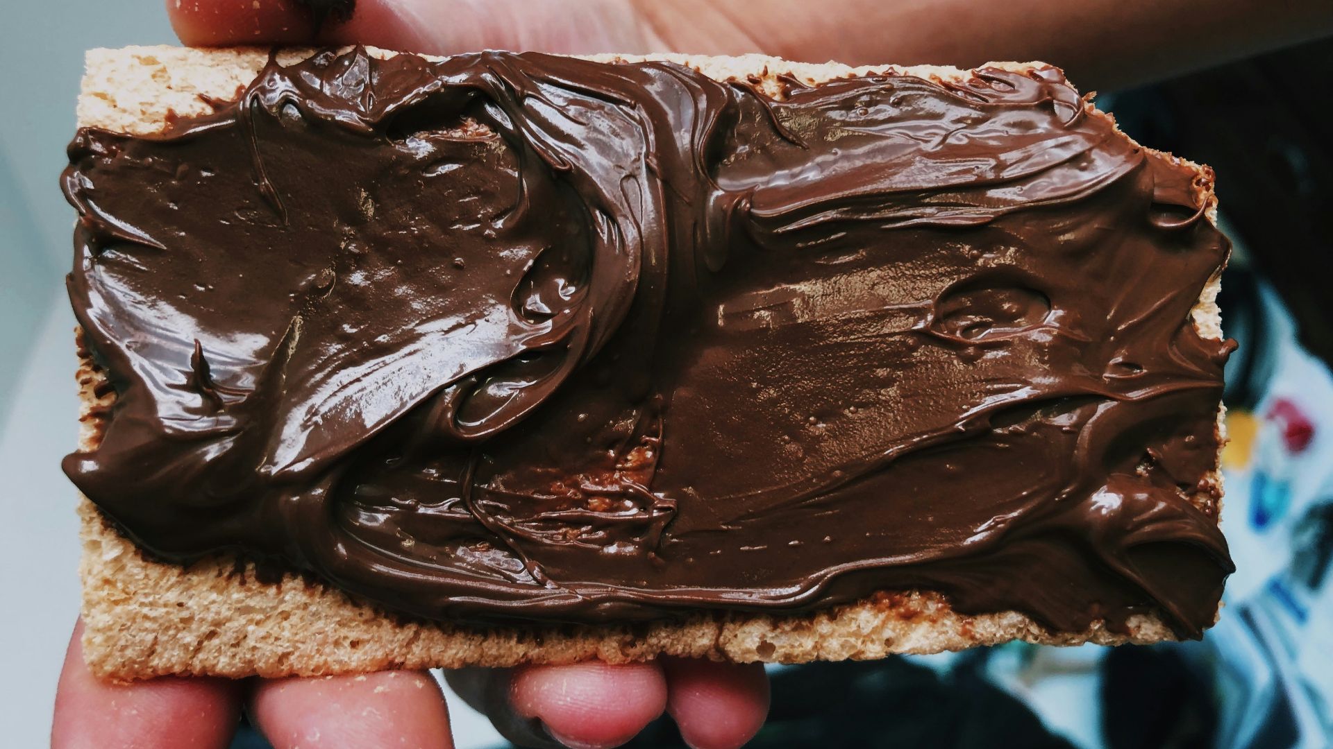 person holding biscuit with nutella