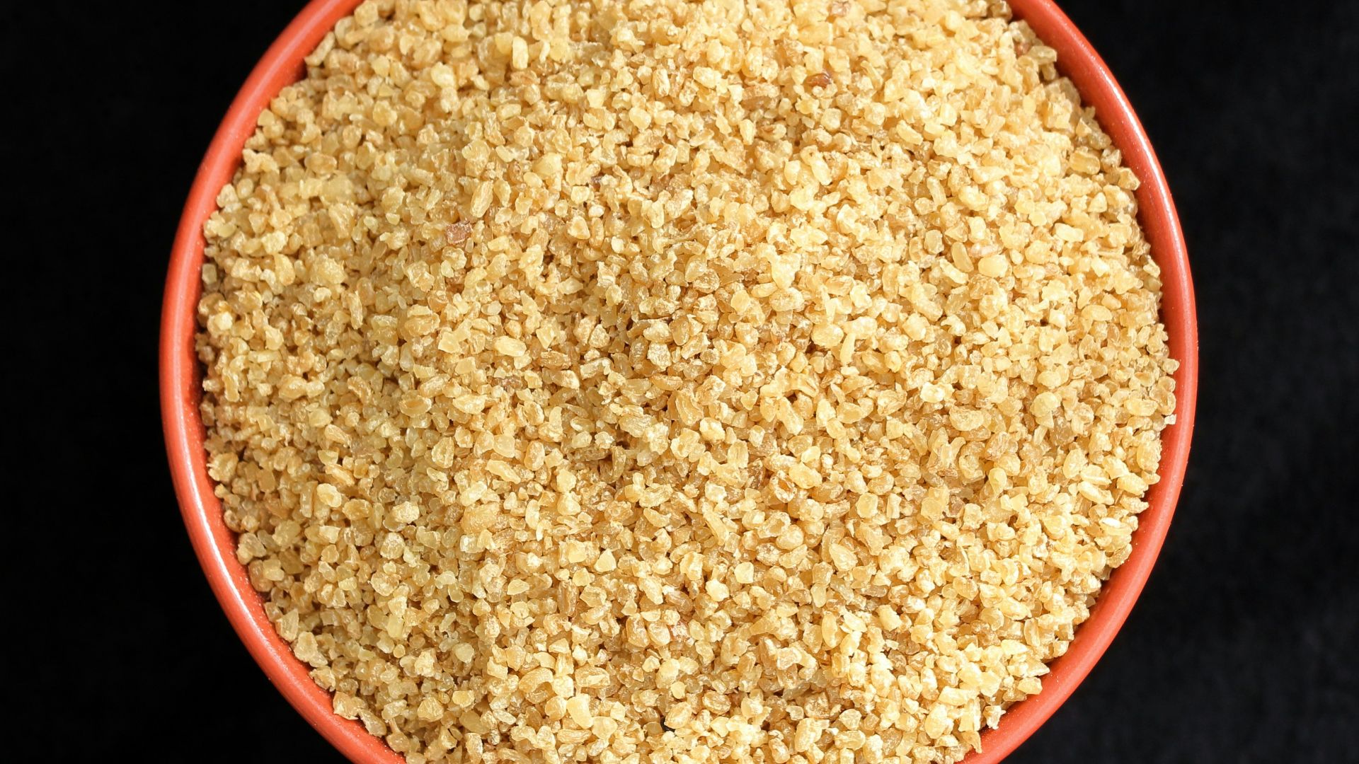 a bowl of sesame seeds on a black background