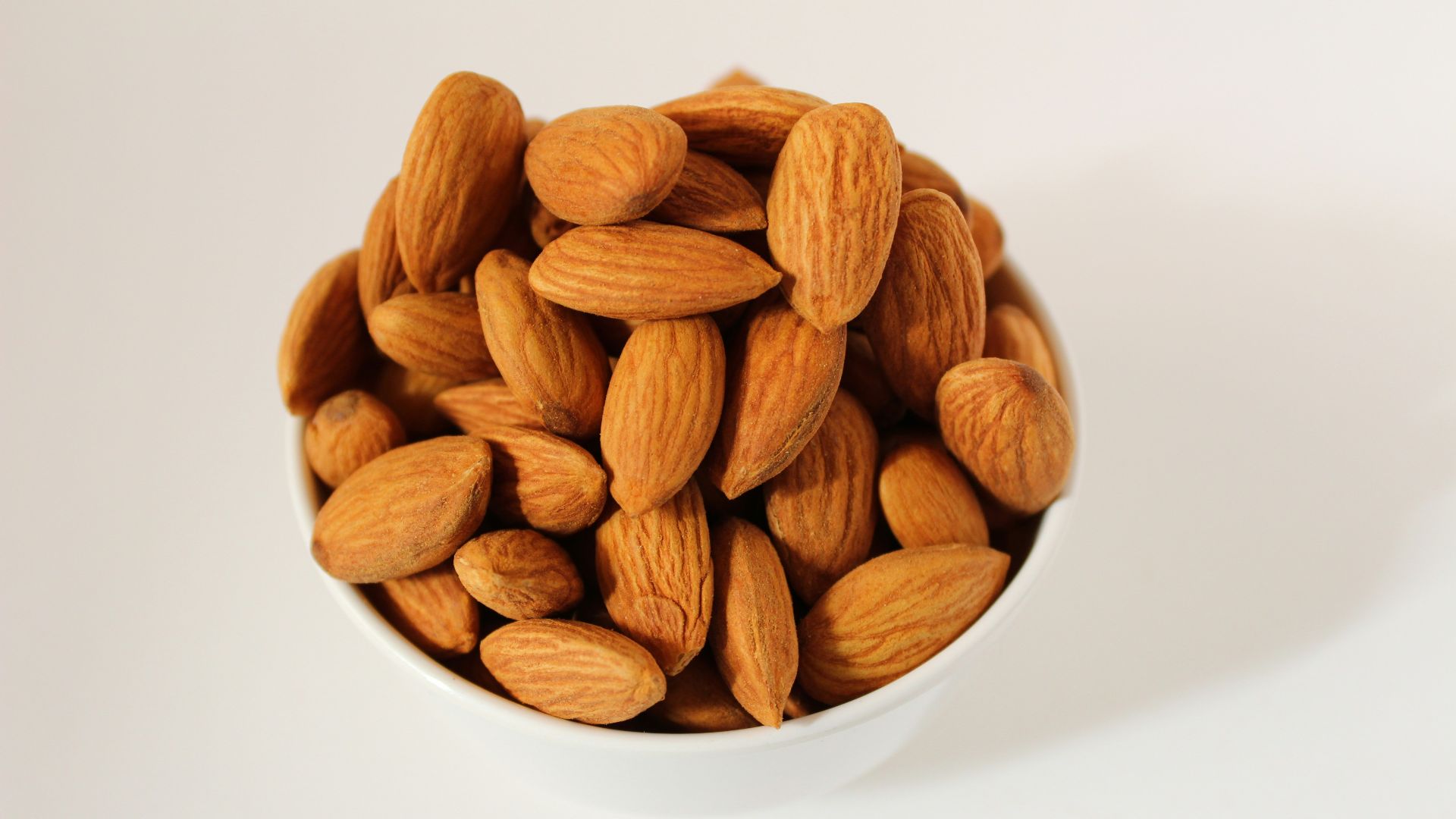 brown almond nuts on white ceramic bowl