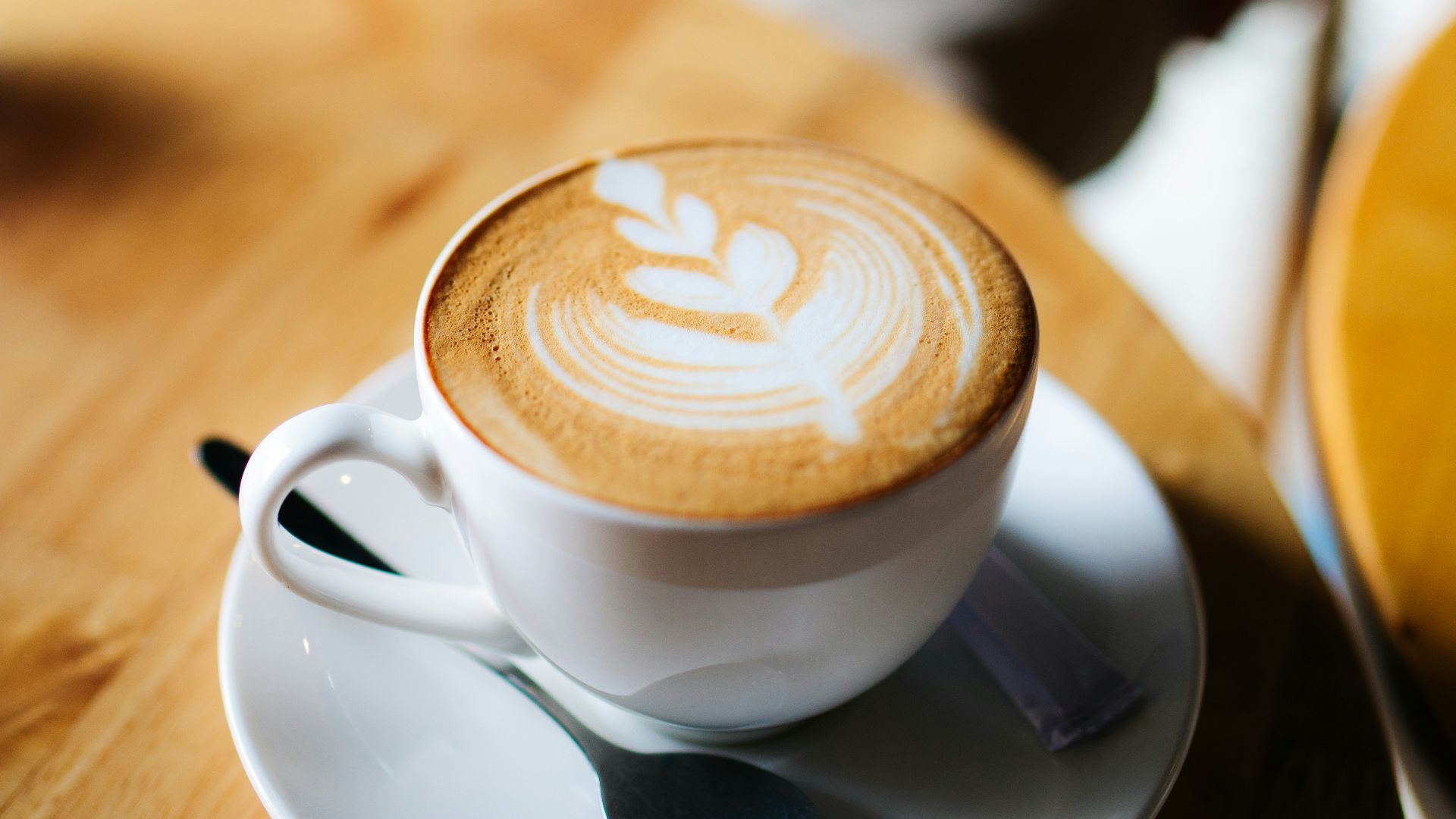 white ceramic cup with latte cafe art on desk