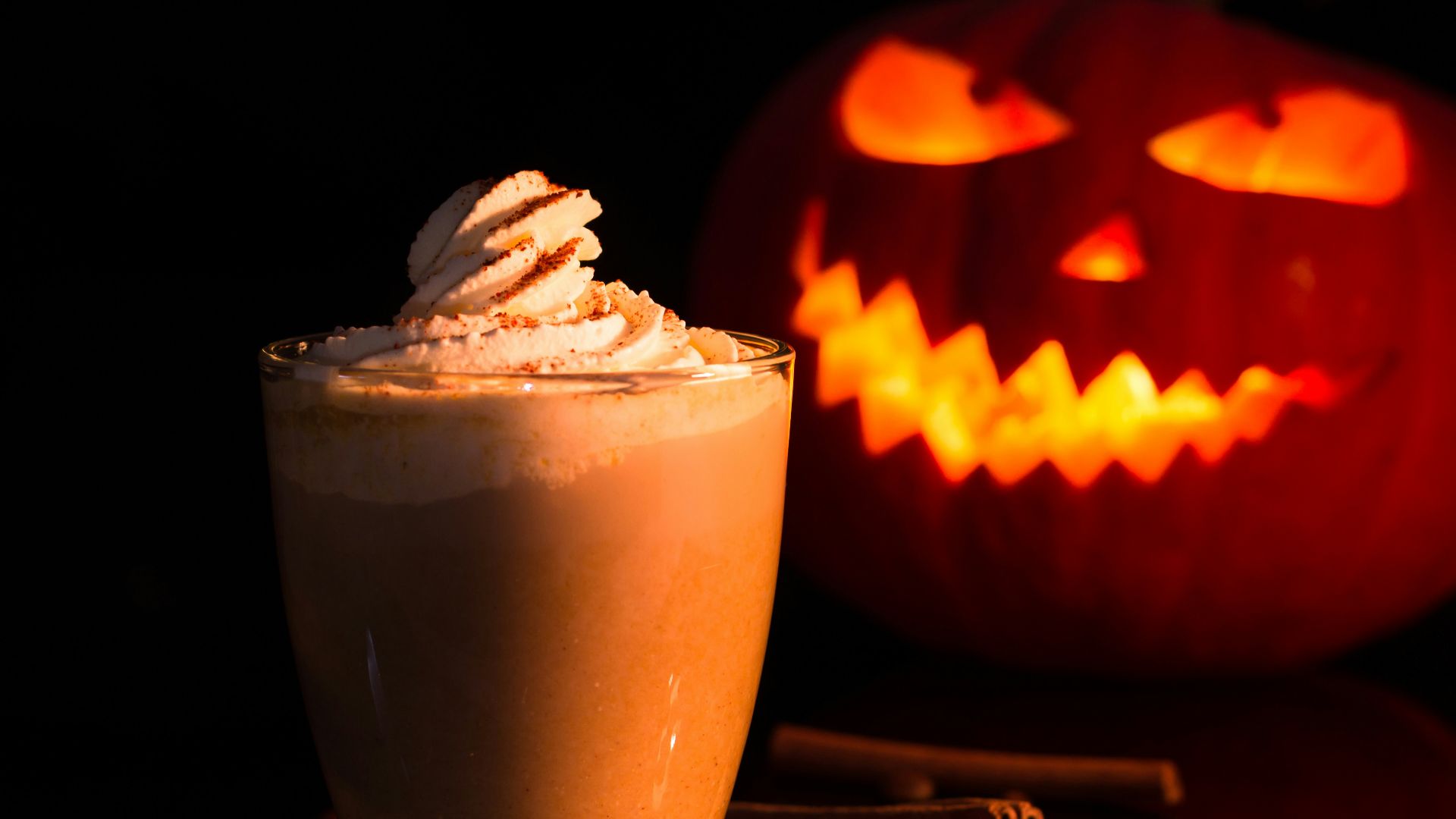 jack o lantern with chocolate drink on brown wooden table