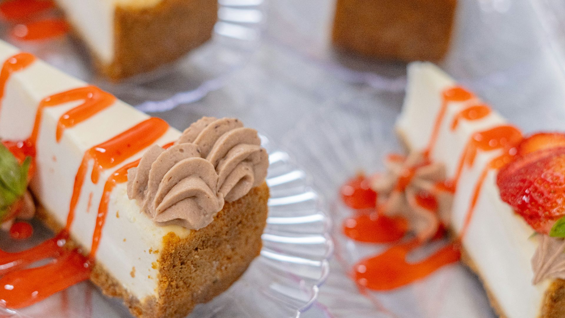 Cheesecake slices with topping and a strawberry drizzle.