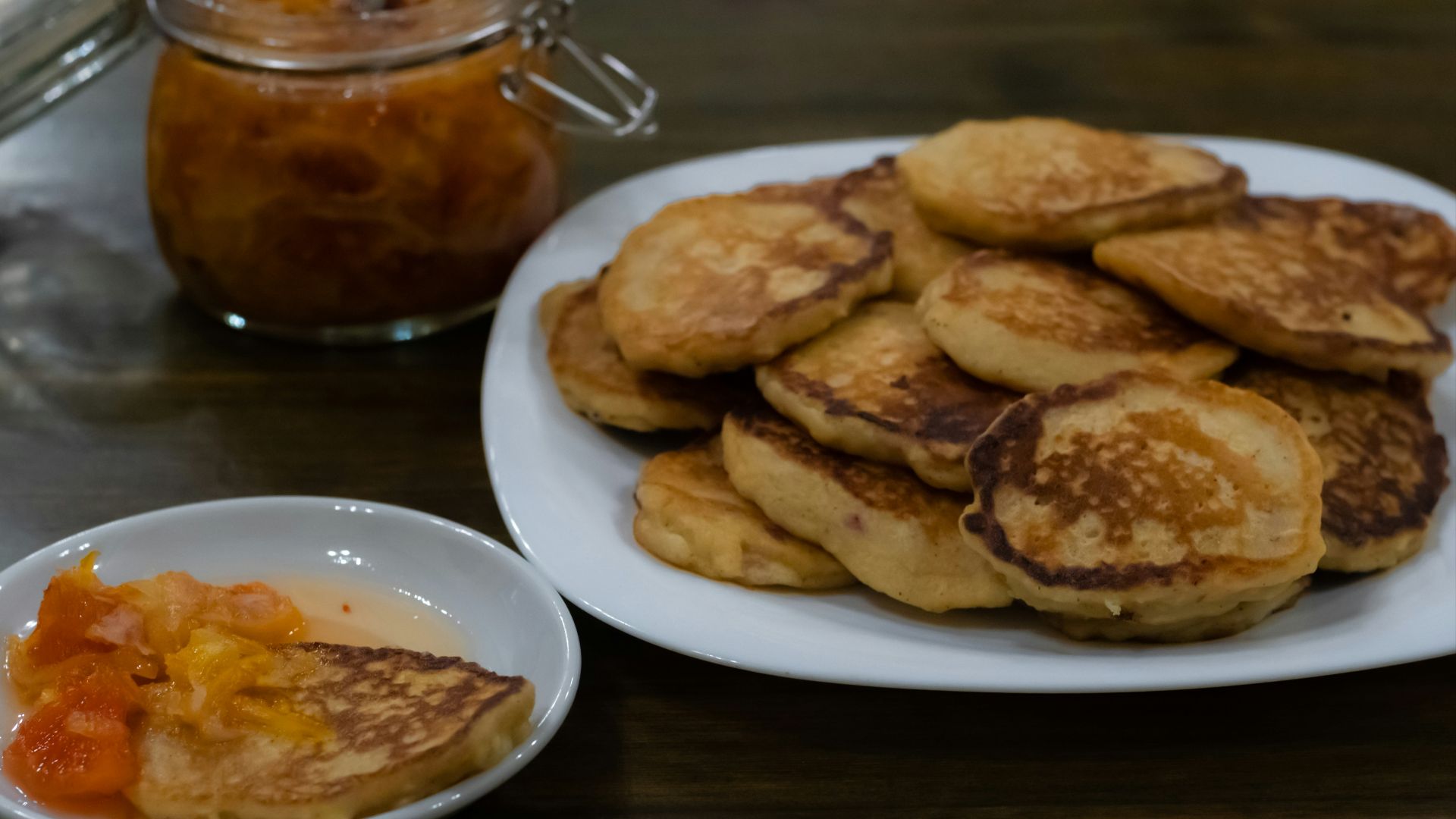 a white plate topped with pancakes next to a bowl of fruit