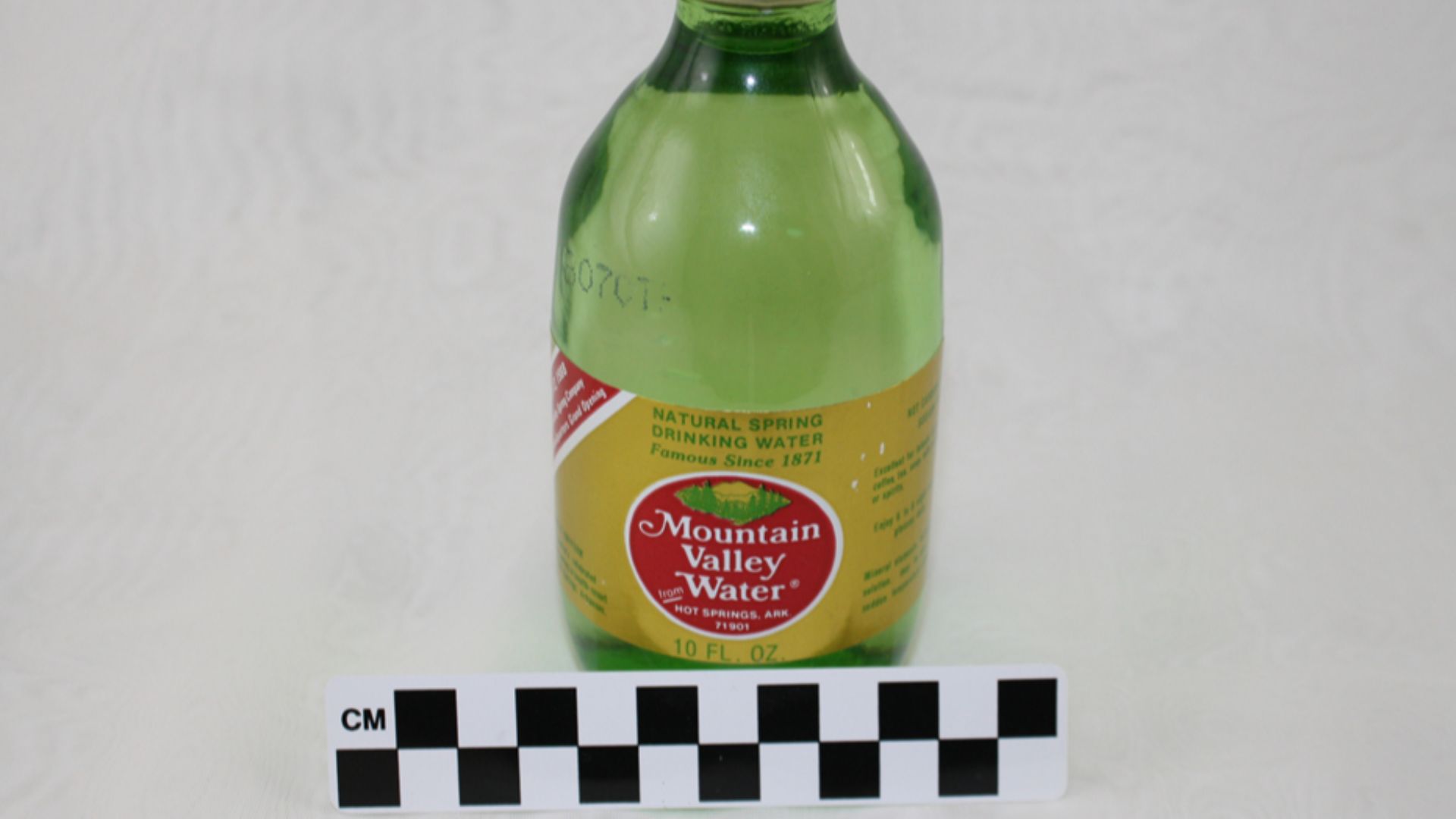 File:Unopened glass water bottle containing mineral water. Green glass, gold label with red circle; white letters on circle read (5d277111-8e24-4582-a764-6d0afcaa86ed).jpg