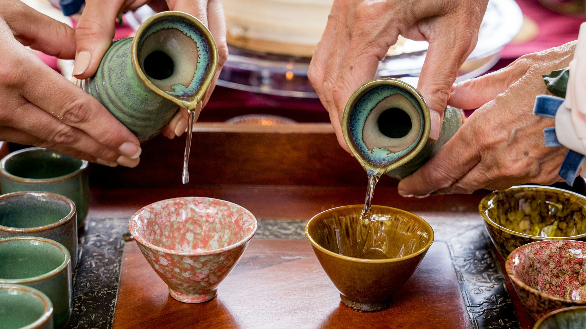 a group of people pouring liquid into small cups