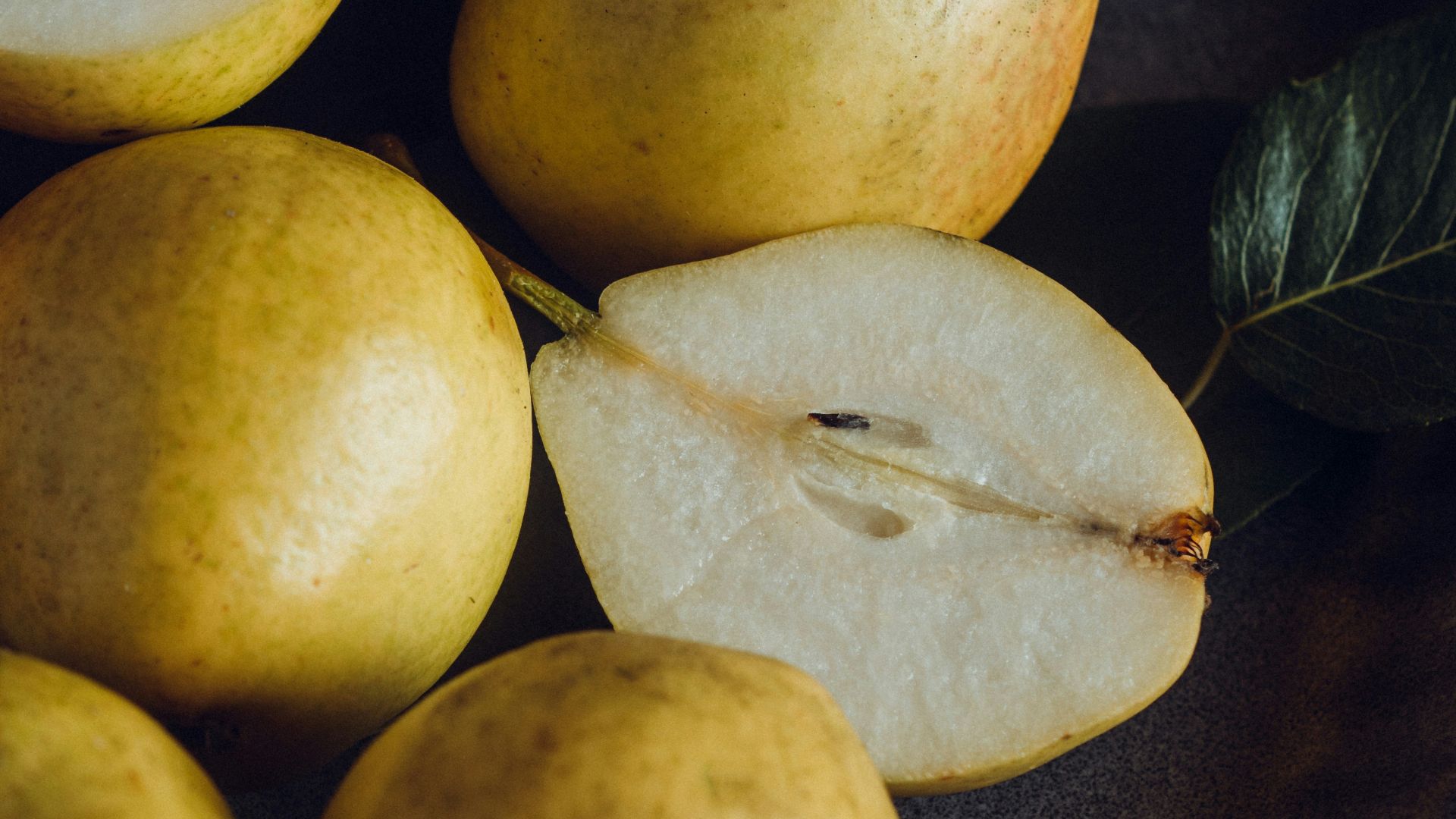 a plate of pears and a leaf on a table