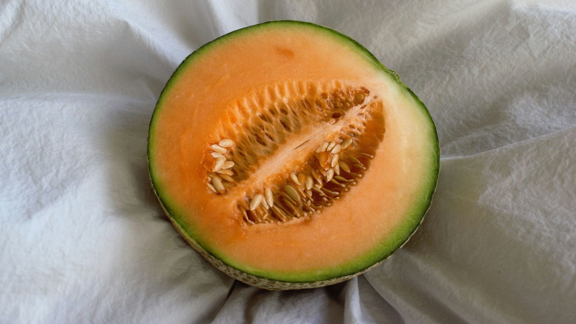a cut in half melon sitting on top of a white cloth